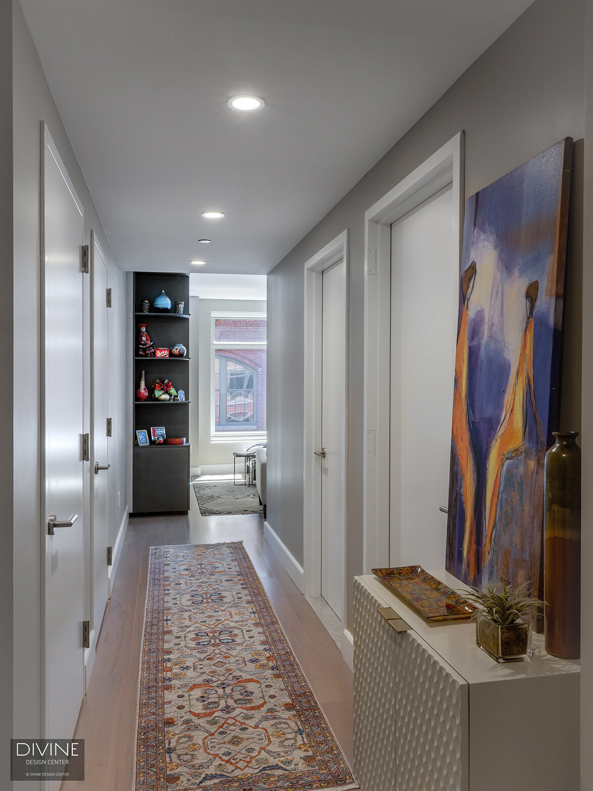  A long narrow hallway inside this north end condo showcases modern, European door systems with art and modern sideboards flanking the white walls. 