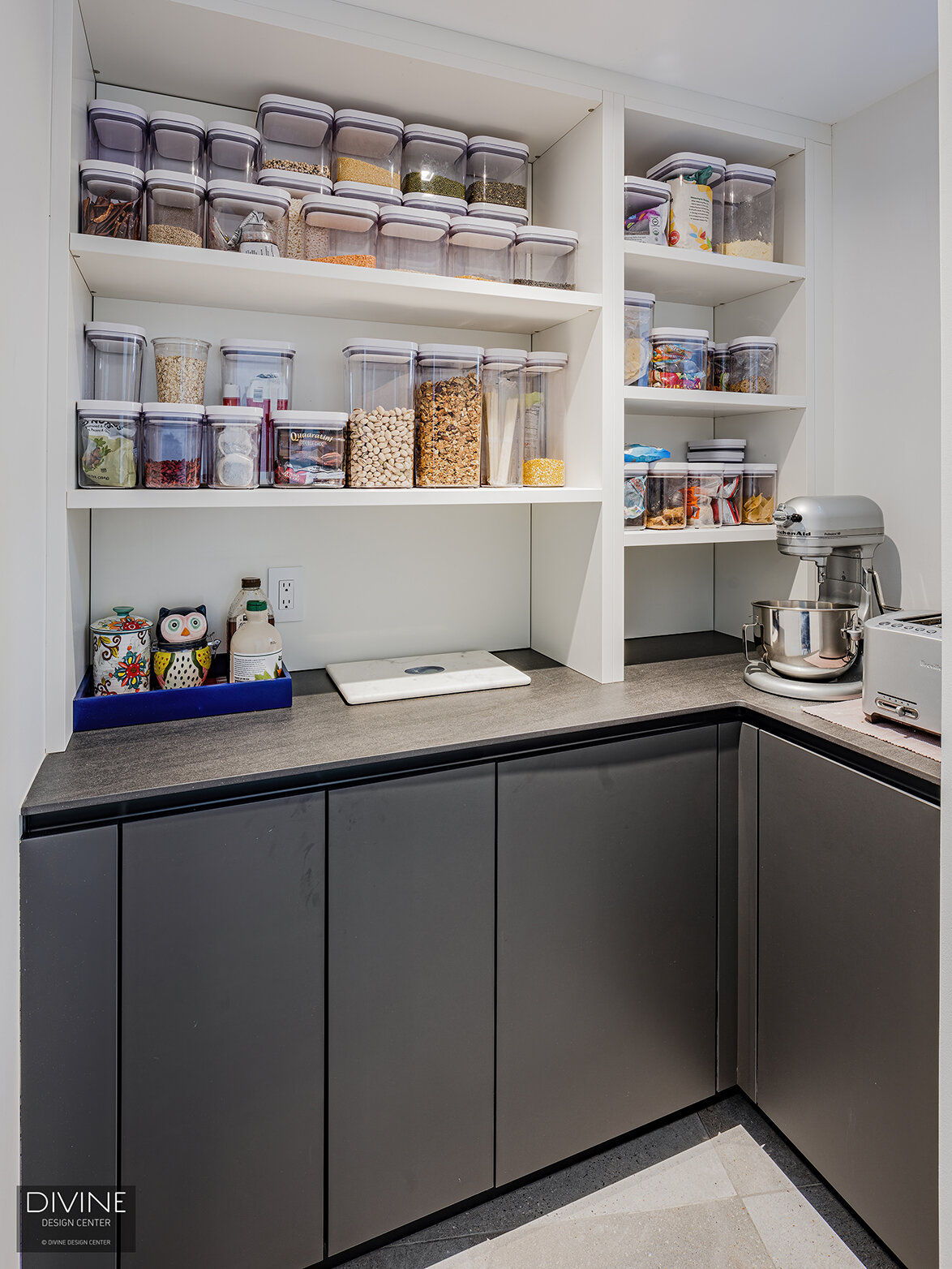  A pantry space with open, niche shelving   above and black, Leicht cabinets below.  