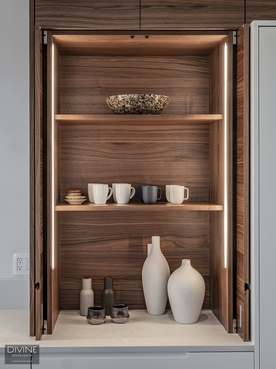  Leicht walnut niche shelving warm up the space with interior lighting and small, minimalist like modern vessels highlighted by the interior cabinet lighting.  