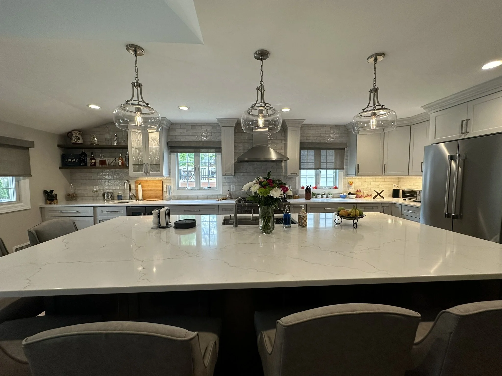 A large center island becomes the focal point of the new kitchen layout. Windows flanking the hood provide beauty and natural light.