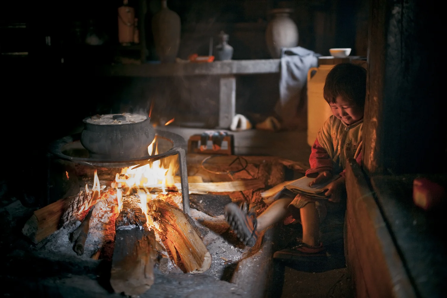 Qiunatong, Yunnan. A child reads near what will be New Year's Eve dinner. The village is primarily agricultural.