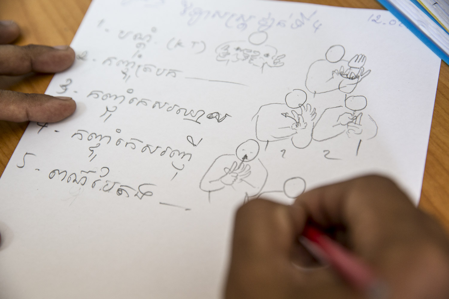  Sam Ath Heang's hands at a language creation session where Cambodian Sign Langauge is being created on a daily basis. Once there is agreement between the participants ,Sam Ath draws the gestures on paper. Later the drawing will be converted to a dig