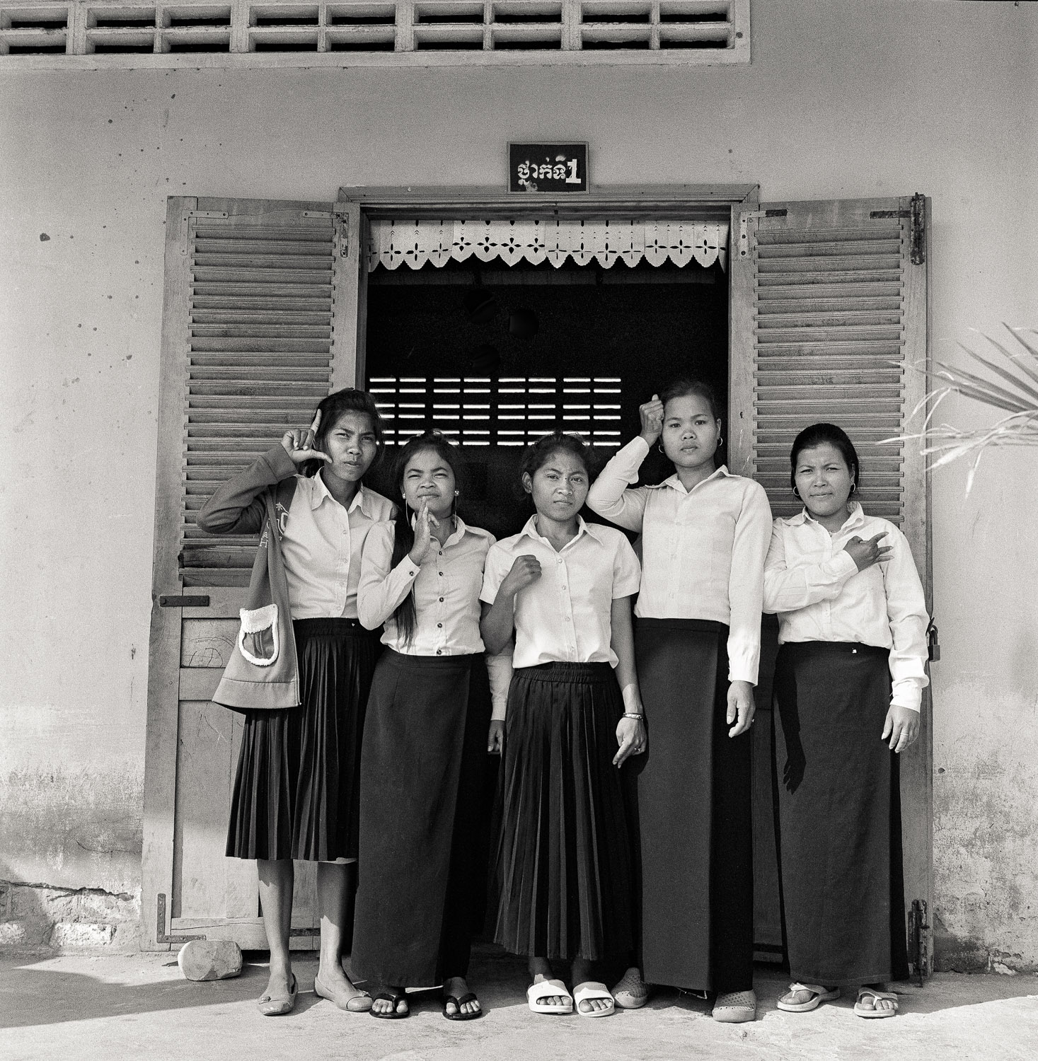  Basic Education students in Kampot, Cambodia.  Each student is showing their name sign in front of their classroom.

Right to left: Yem Sreynuan, Khoeum Pheanh, Min Chay, Chhoeul Mom (2nd year Basic Education Student, all other are 1st year students