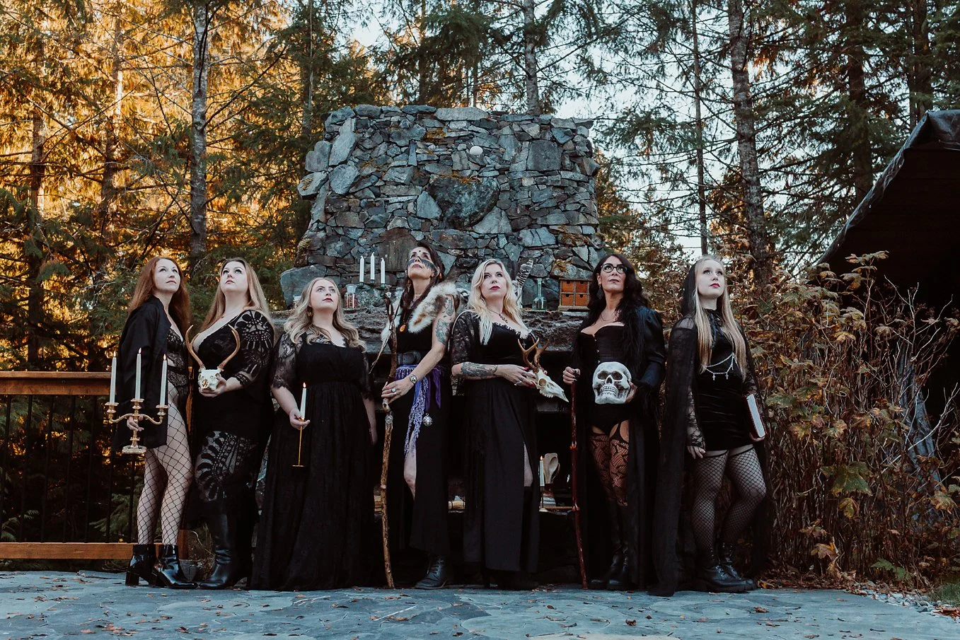 group of women gathered as a witches coven in front of a stone fireplace