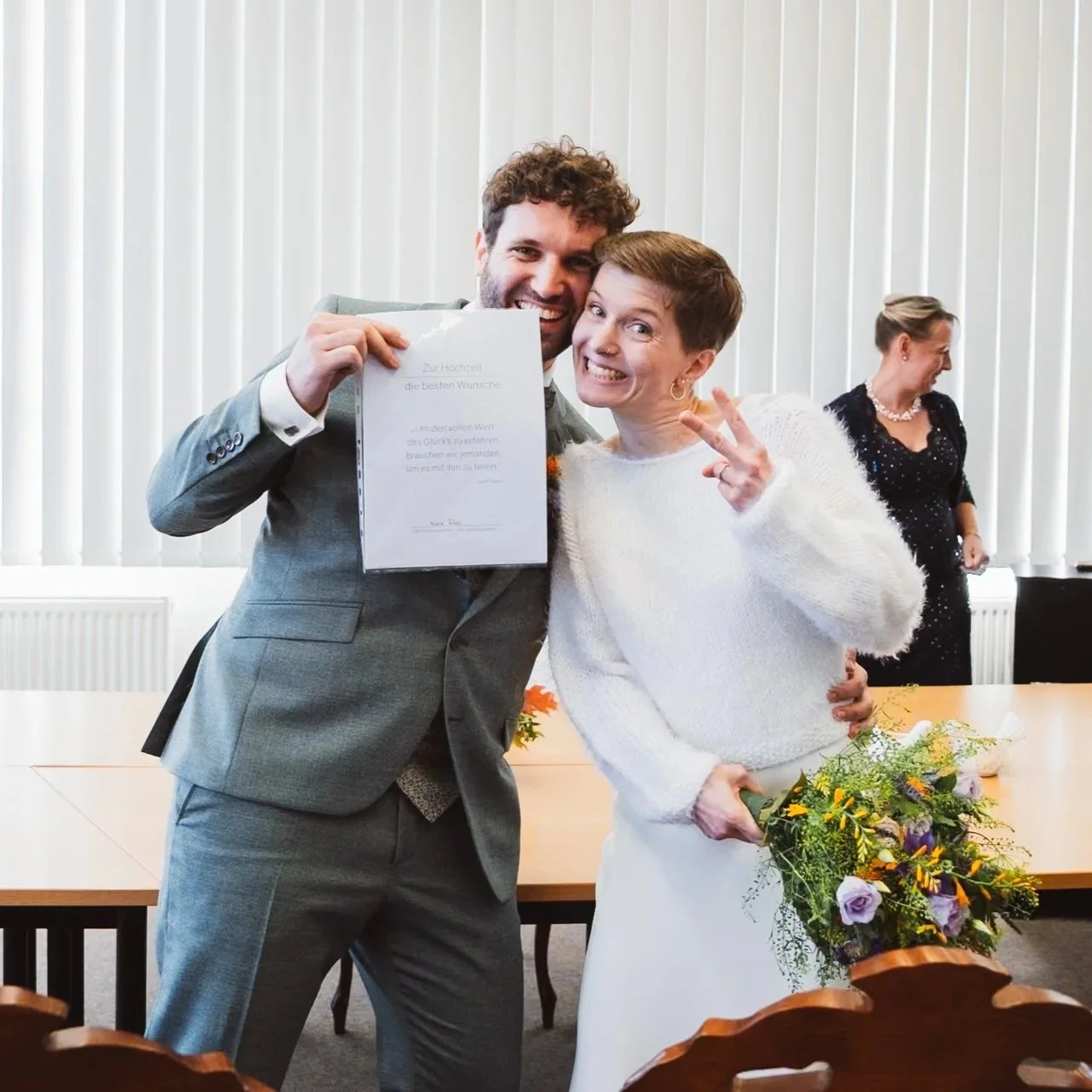 Strahlendes Hochzeitspaar mit Urkunde direkt nach der Trauung