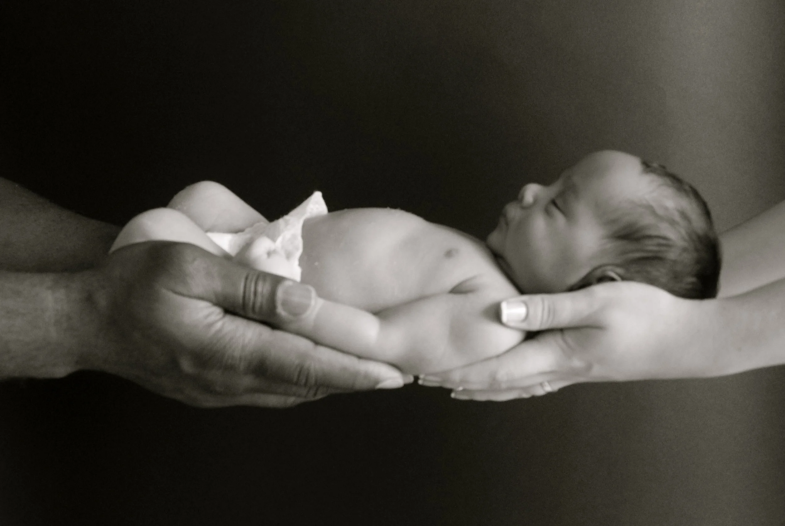A close-up black and white photo of a  infant being held up