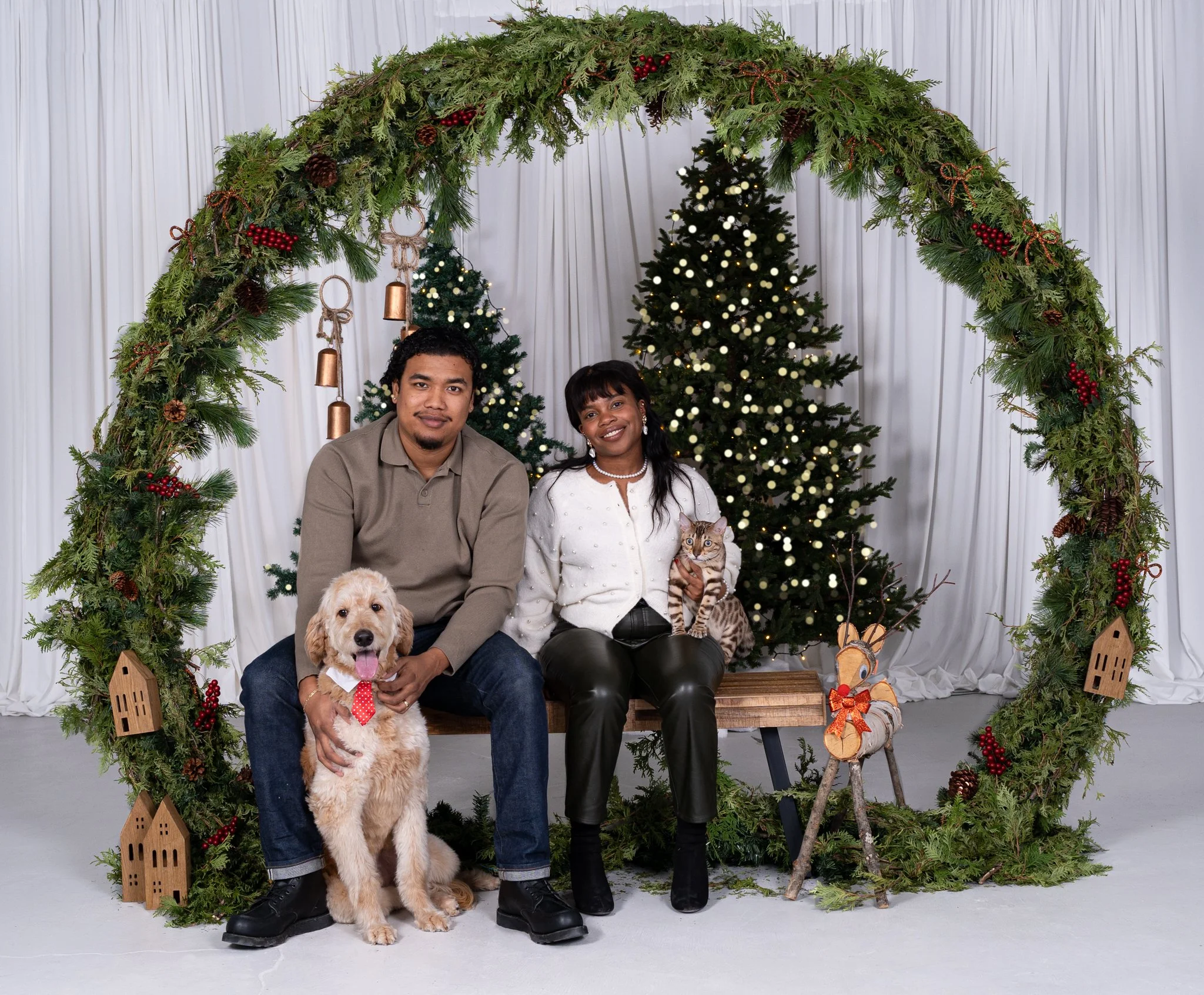 A couple sitting in front of a Christmas tree with a dog