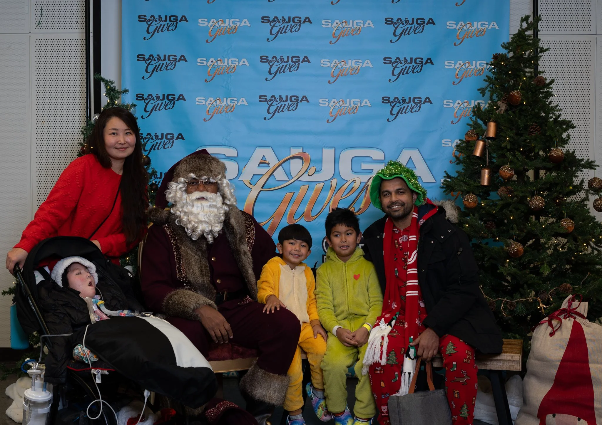 A group of people posed with Santa Claus at the 2025 Saga Gives Christmas holiday event