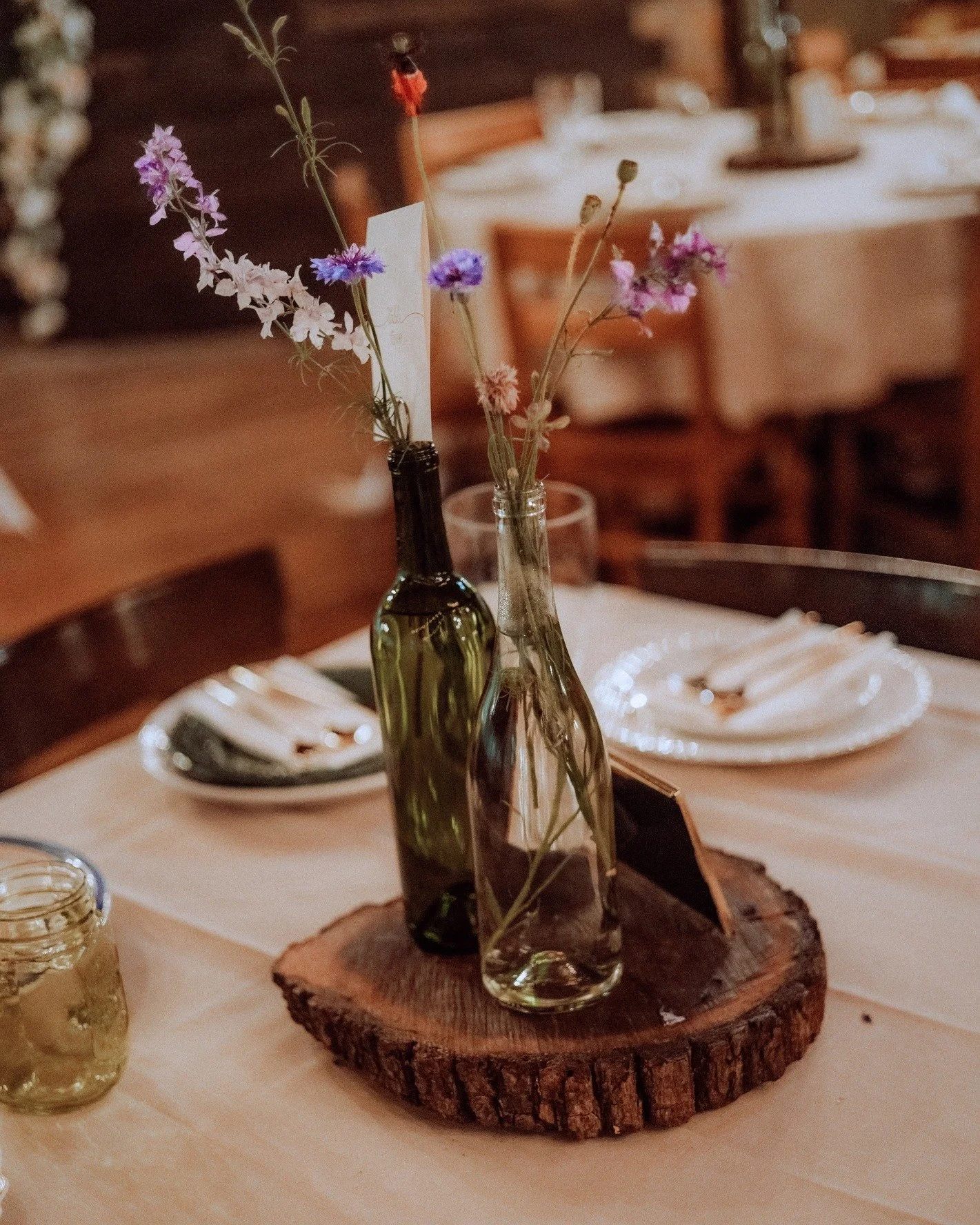 "Wine" down the night in our reception hall. 🍾✨💐 

The Colemans repurposed wine bottles for their rustic centerpieces. We love a sustainable glow-up!

📸 @pine_hills_media 

 #cabinwedding #merryledgesinthewoods #weddingcenterpiecesideas
