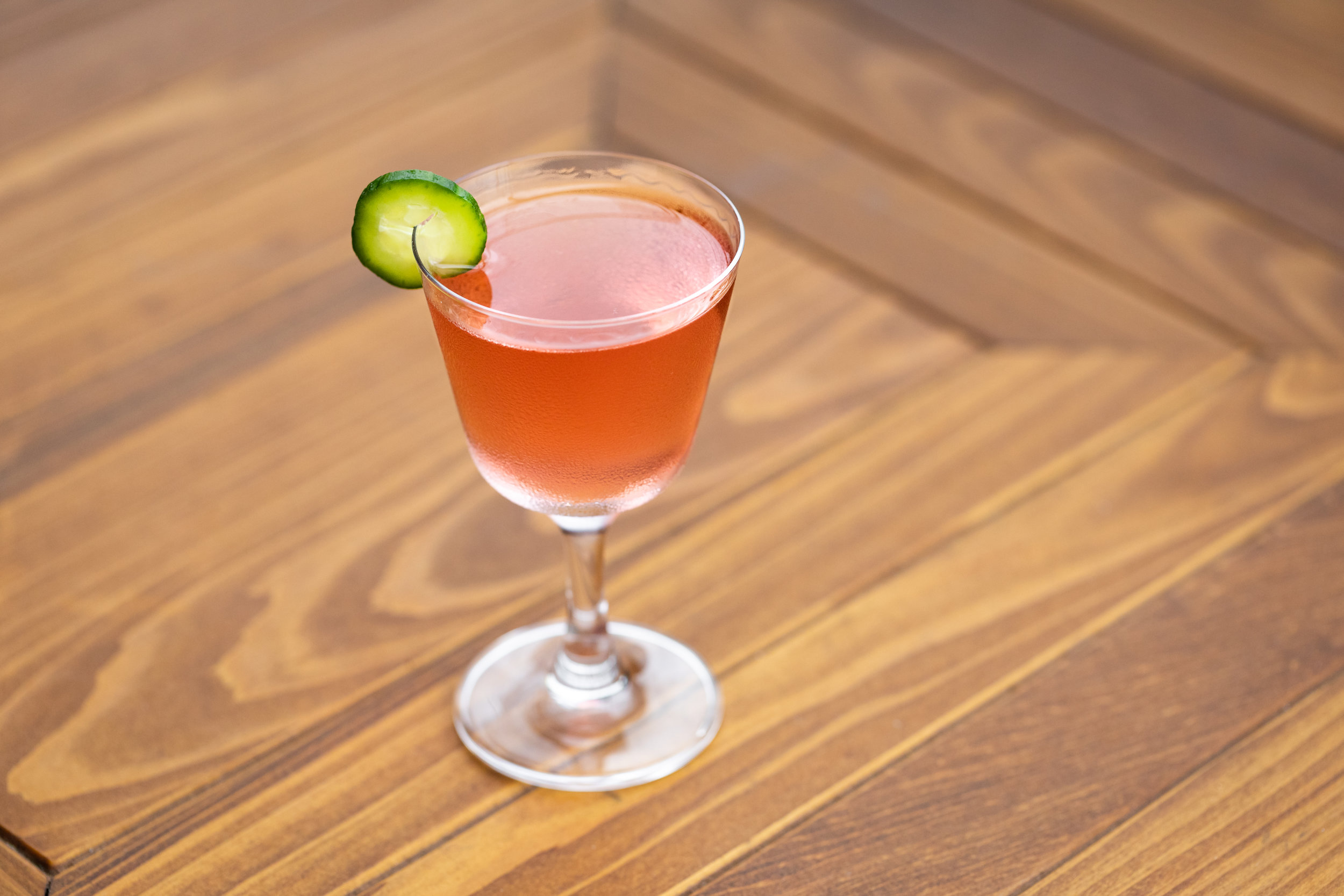 photo of a cocktail garnished with a cucumber slice