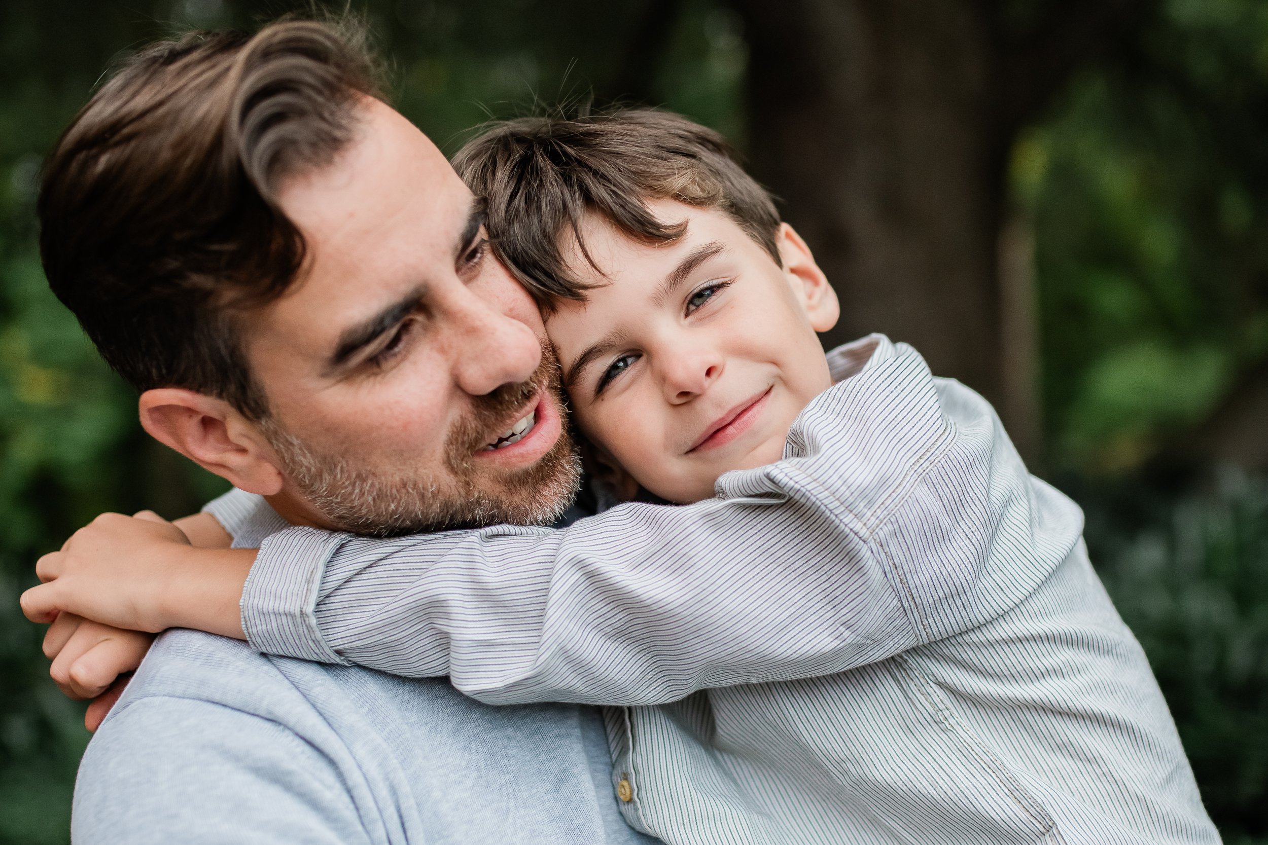  Dad snuggles young son who is looking at the camera. 