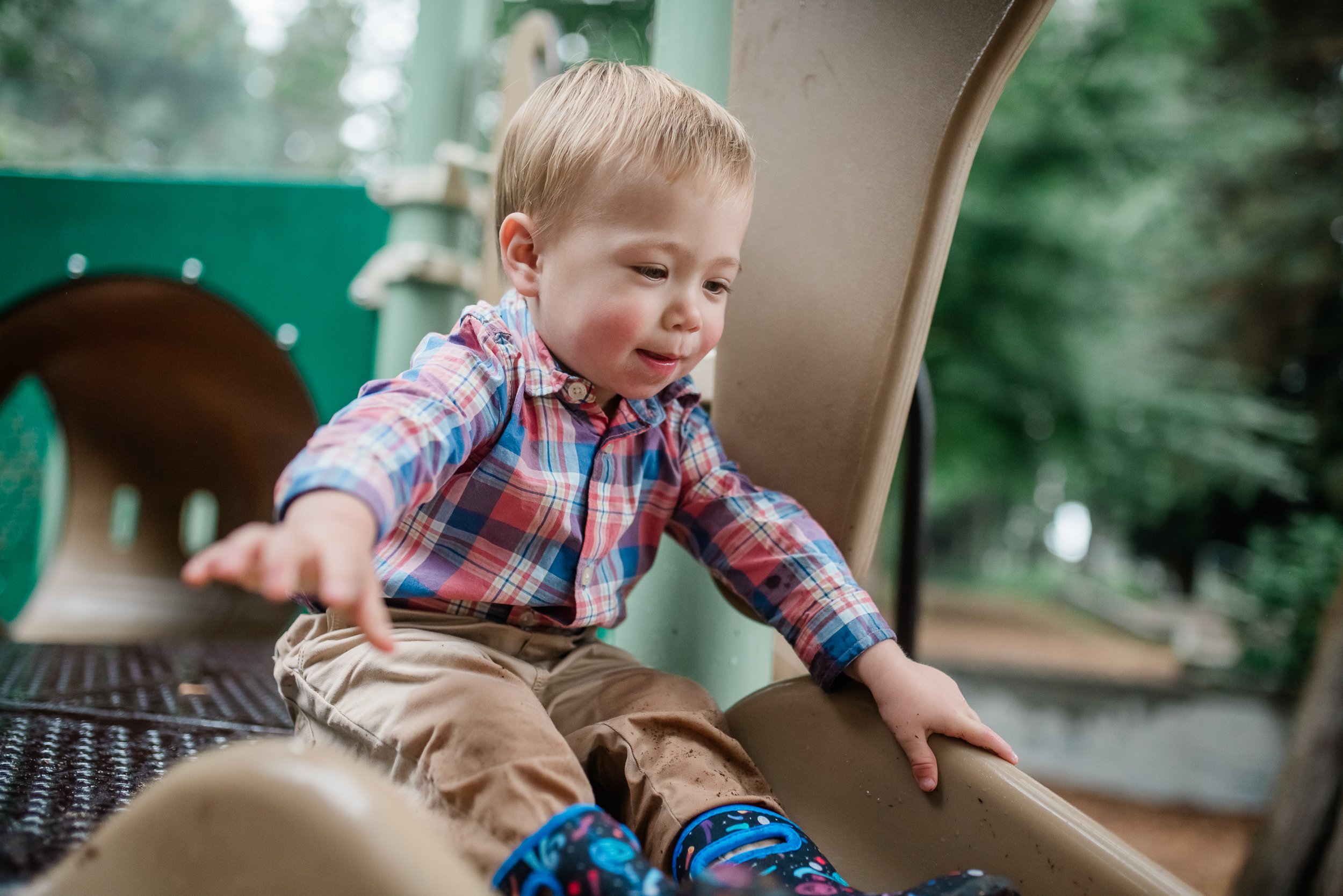  Toddler boy going down a playground slide during a session. 