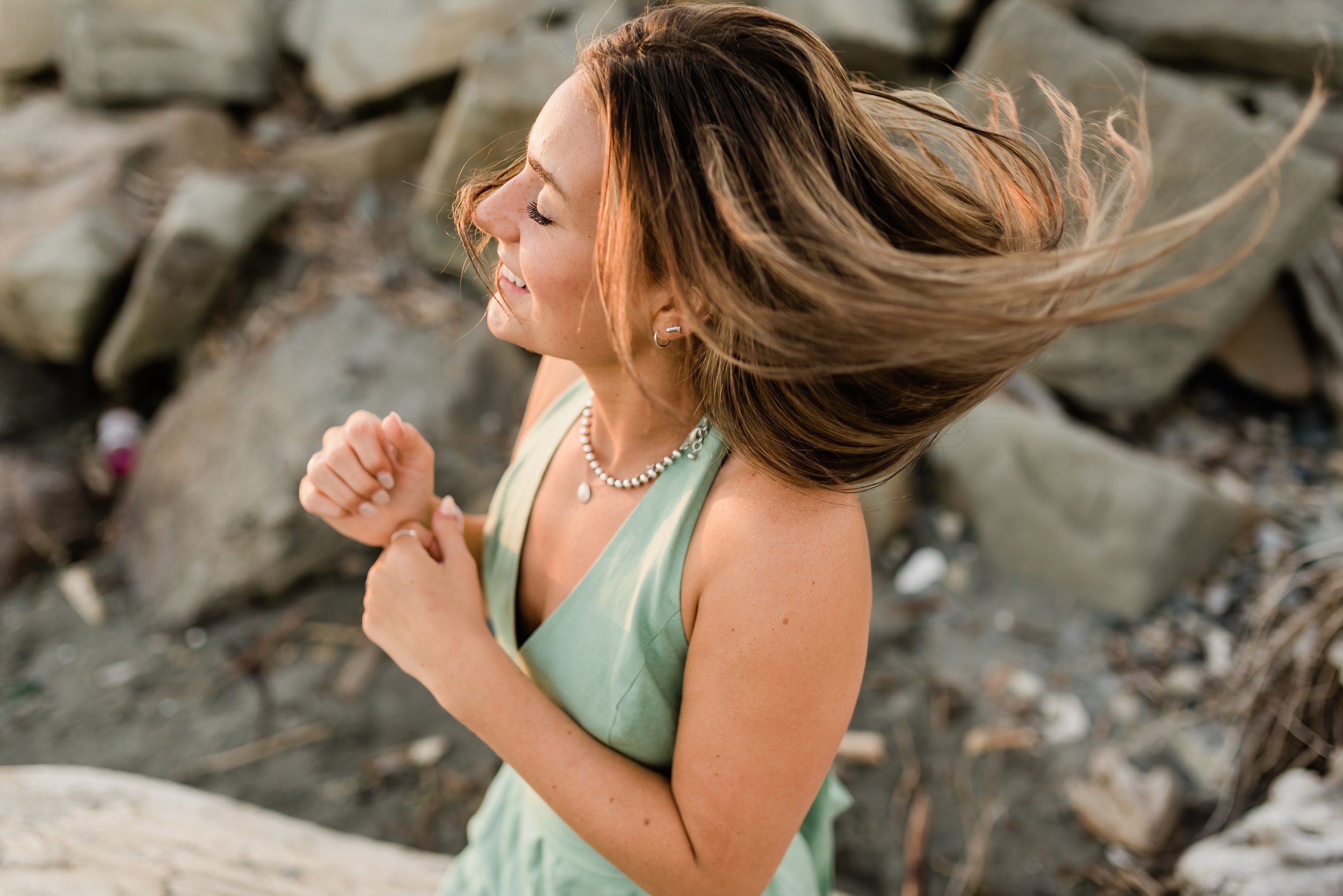  High school senior girl shakes out her hair on the beach in Seattle. 
