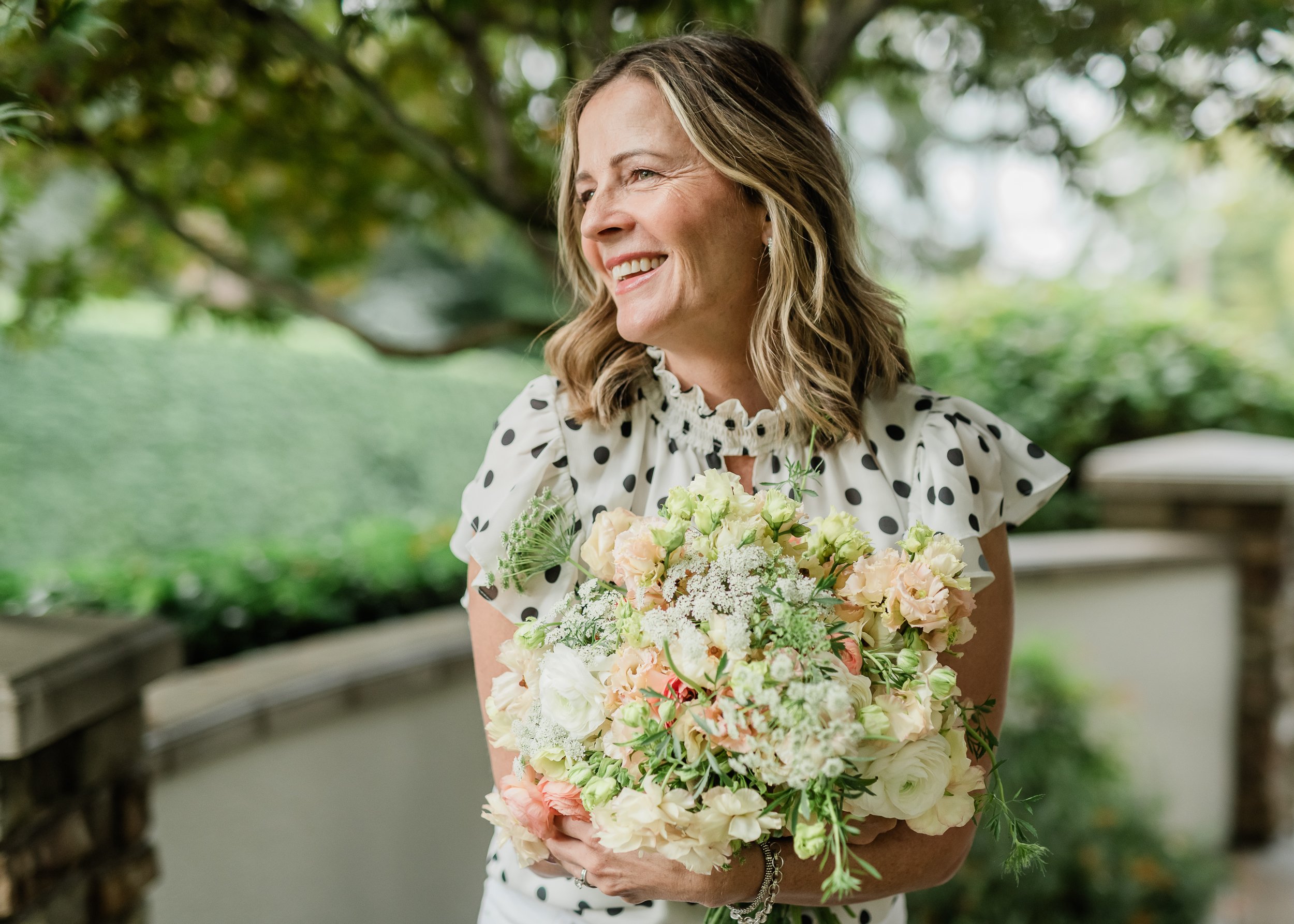  Florist looks into sunshine while holding her freshly made bouquet. 