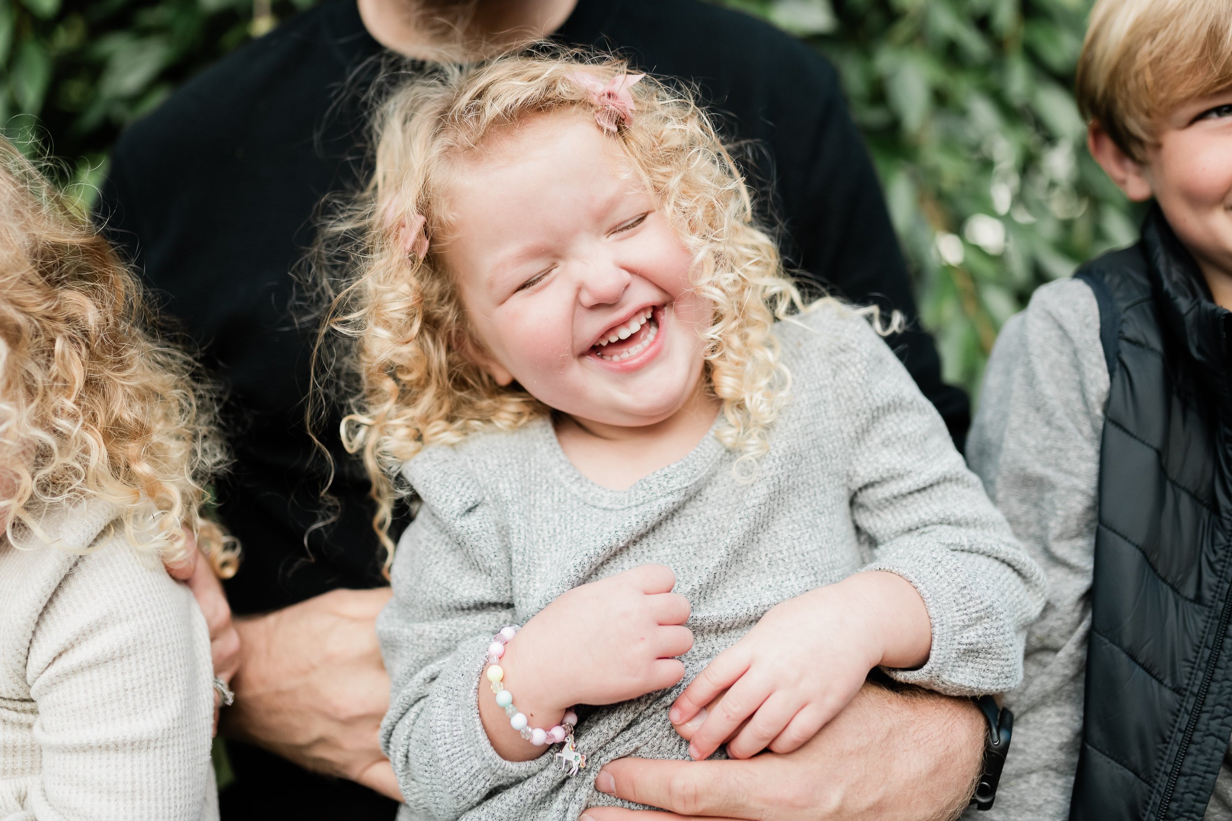  Little girl giggles when her daddy tickles her during a photo session. 