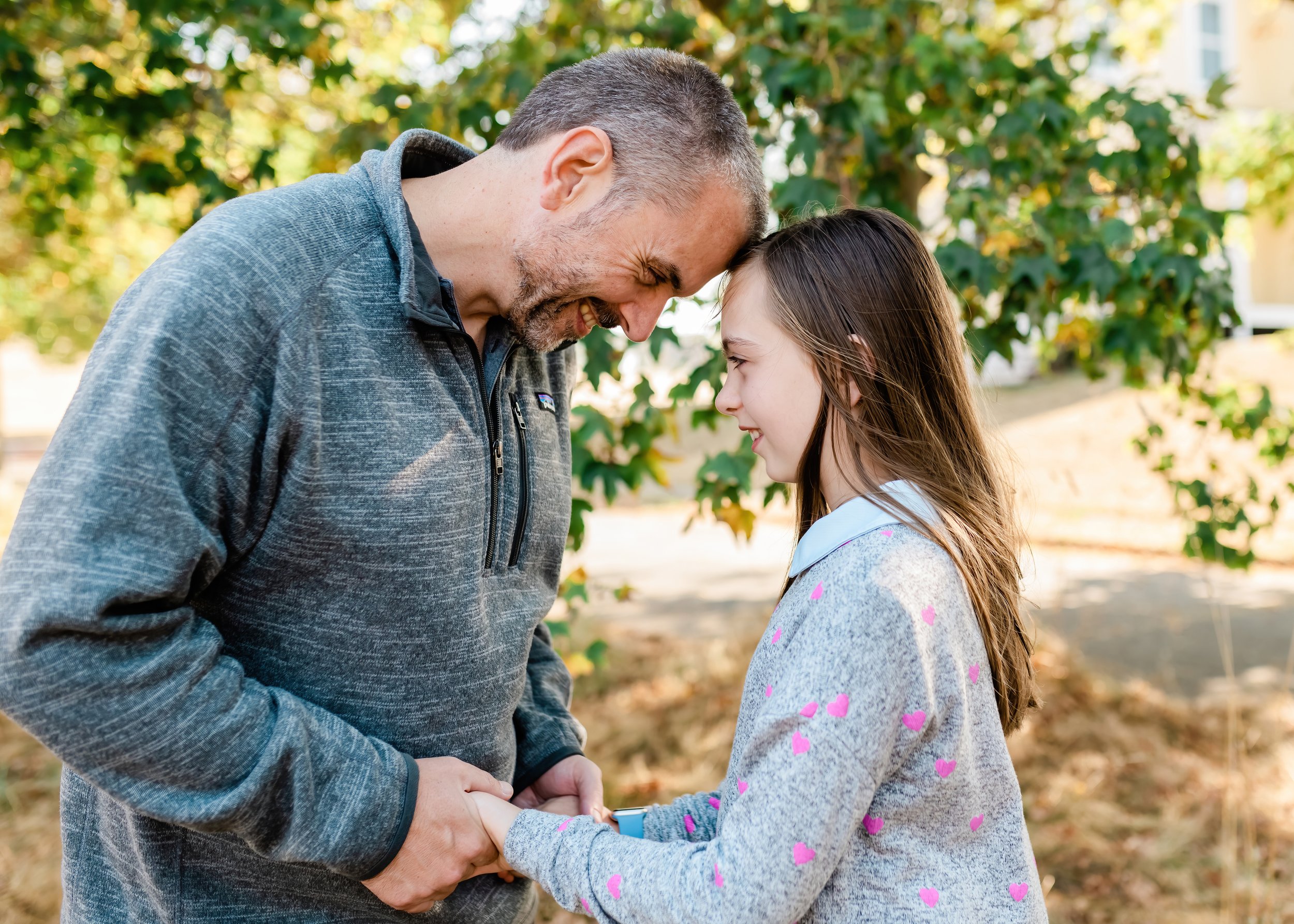  Dad and daughter touch foreheads in a field. 