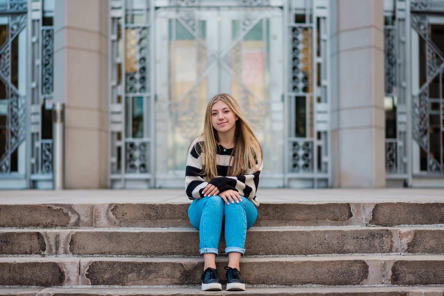  High school senior girl sitting on the stairs in front of Asian art museum. 