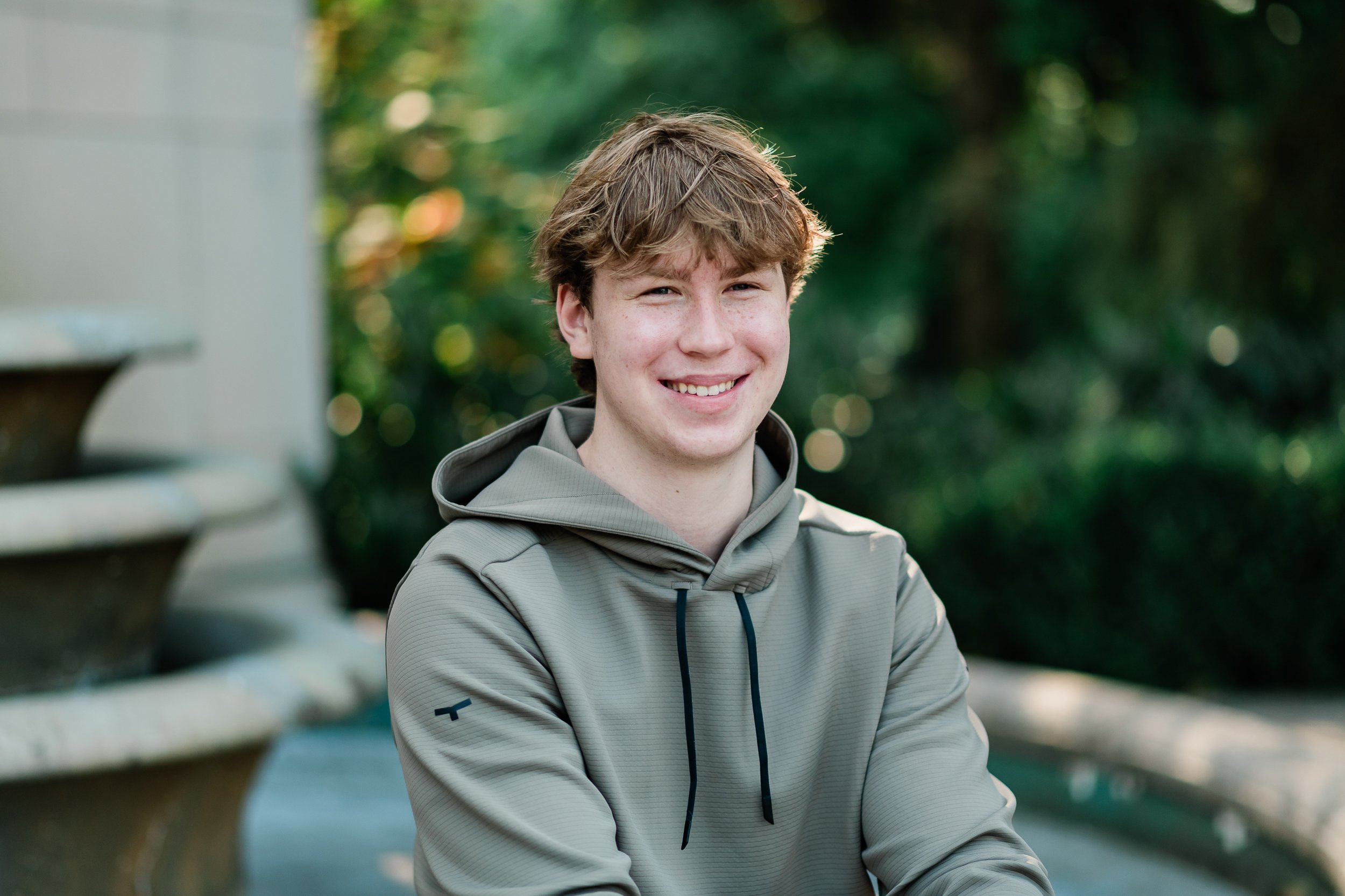  Teenage boy smiling in front of a fountain. 