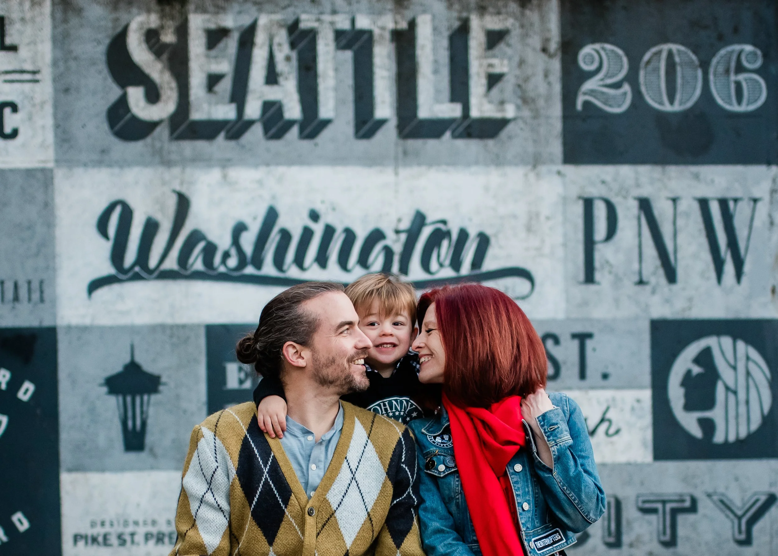 Photo of a family of three with a small child posing in front of a mural in downtown Seattle by Katie Niemer Photography