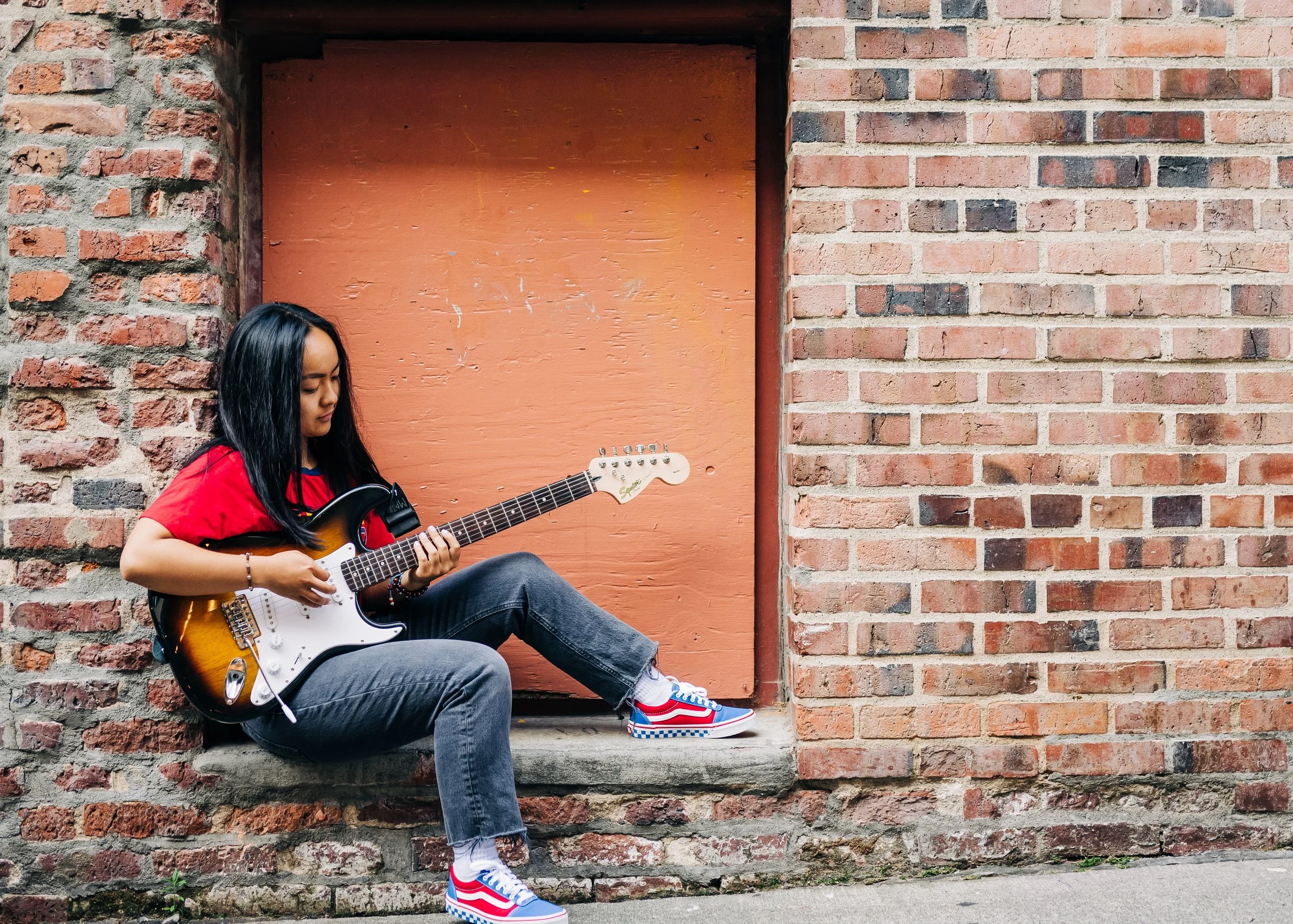 High school senior poses with her guitar in Post Alley at Pike Place Market, Seattle WA by Katie Niemer Photography