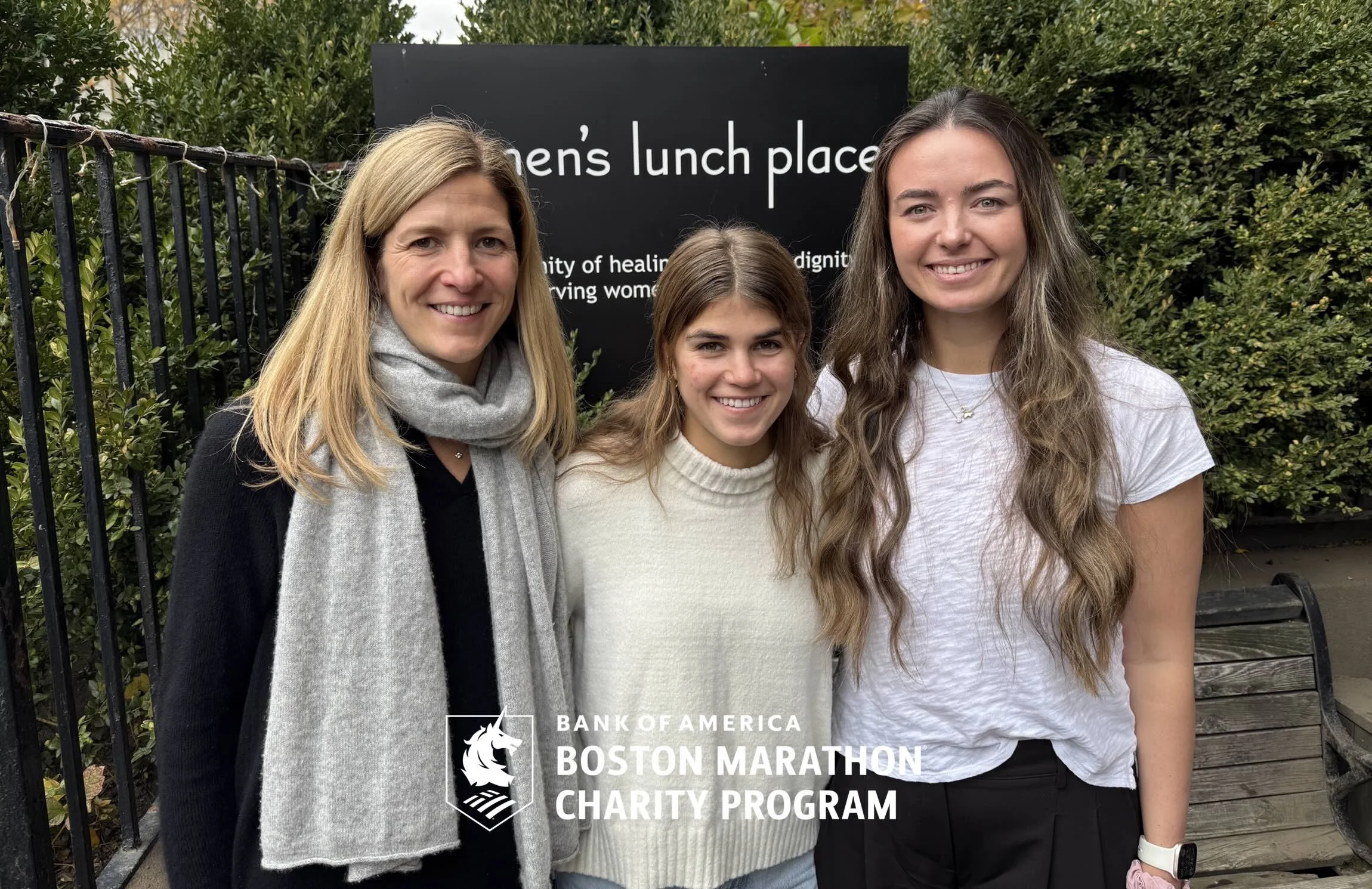 Three Marathon runners standing in front of the Women's Lunch Place sign.
