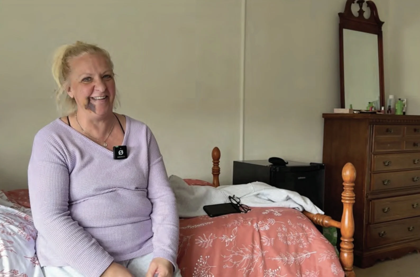 A guest sitting on her bed in her private room.