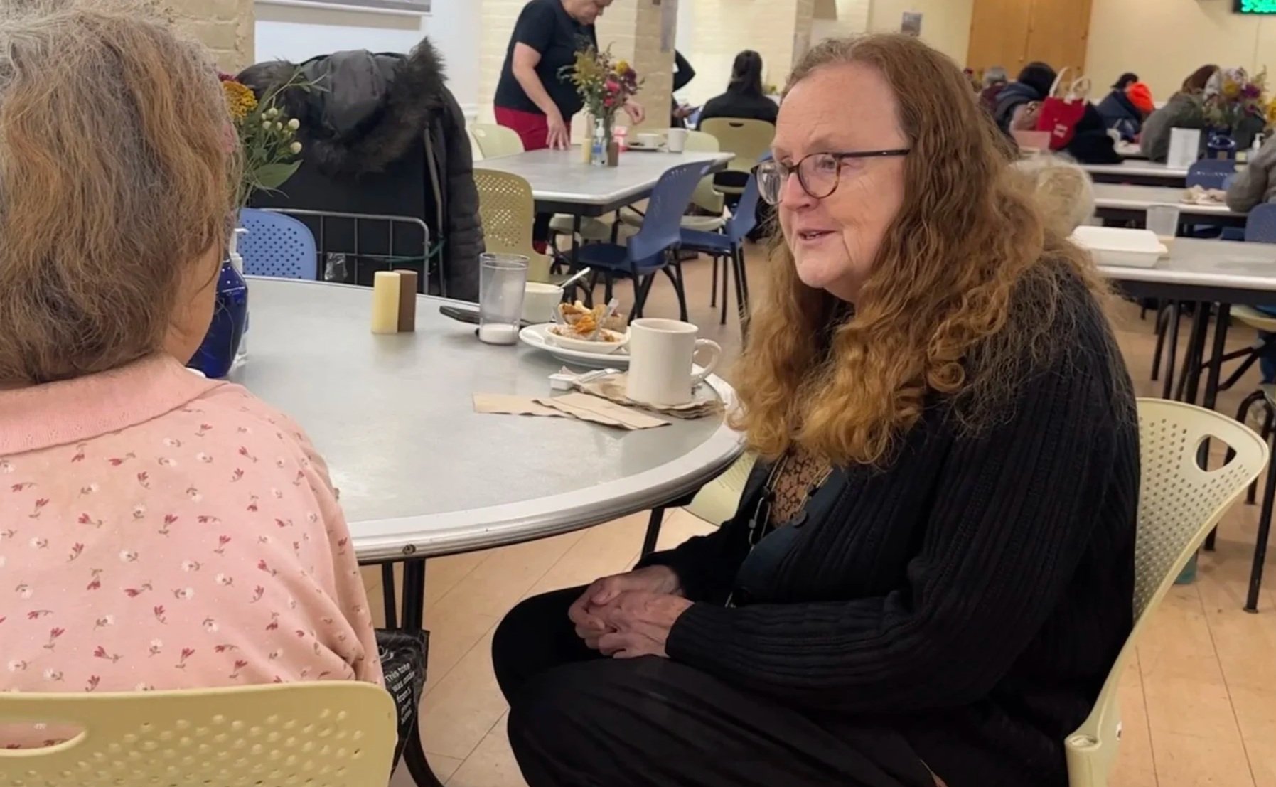 Dr. Eileen Reilly speaks with a guest at a table in the community dining room.