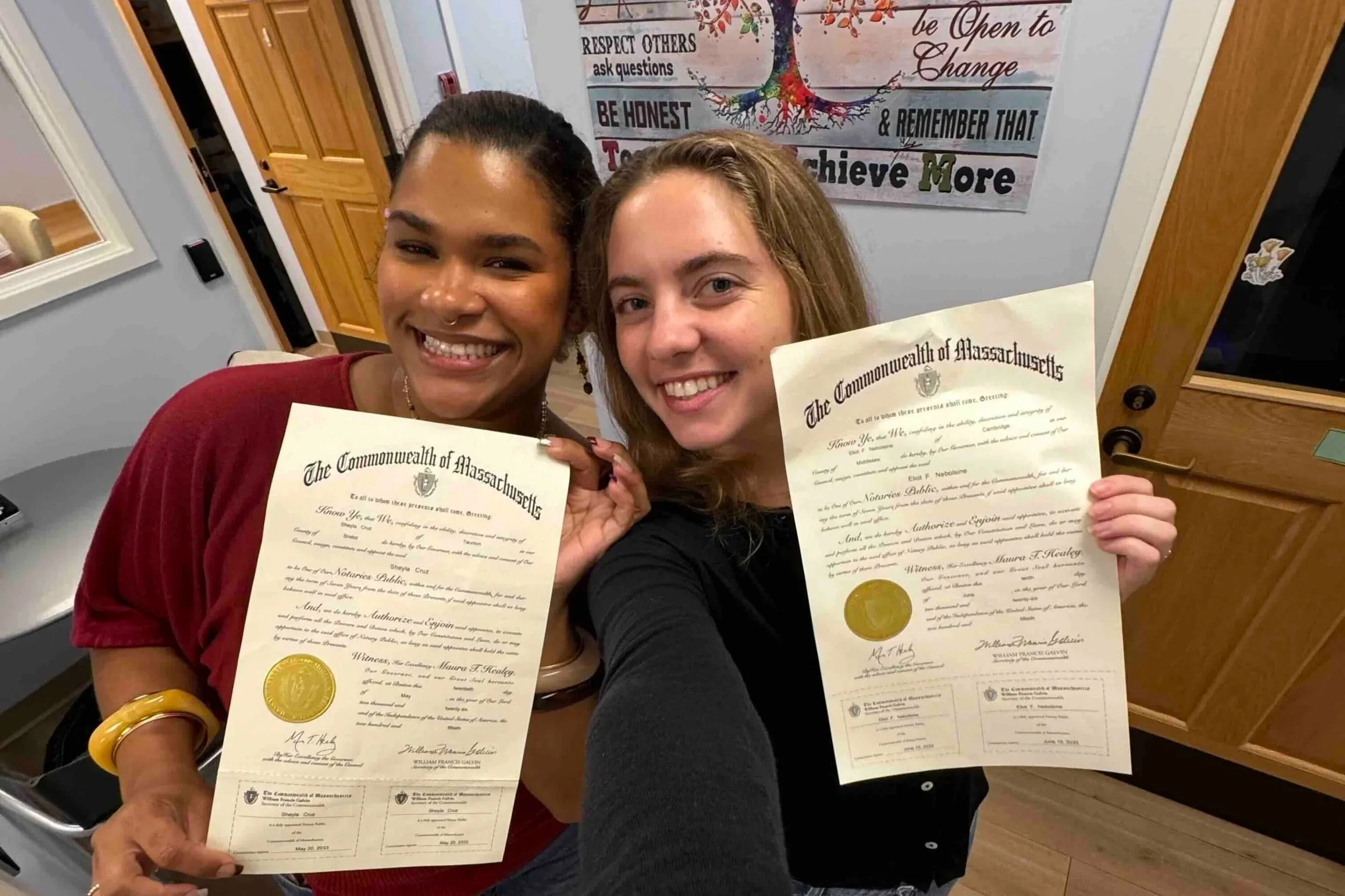 Two smiling case managers hold up their certificates in the WLP office.