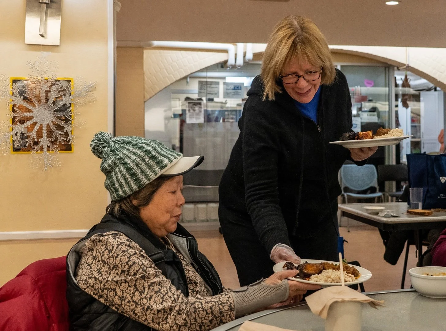 A volunteer serves a guest of Women's Lunch Place at her table.