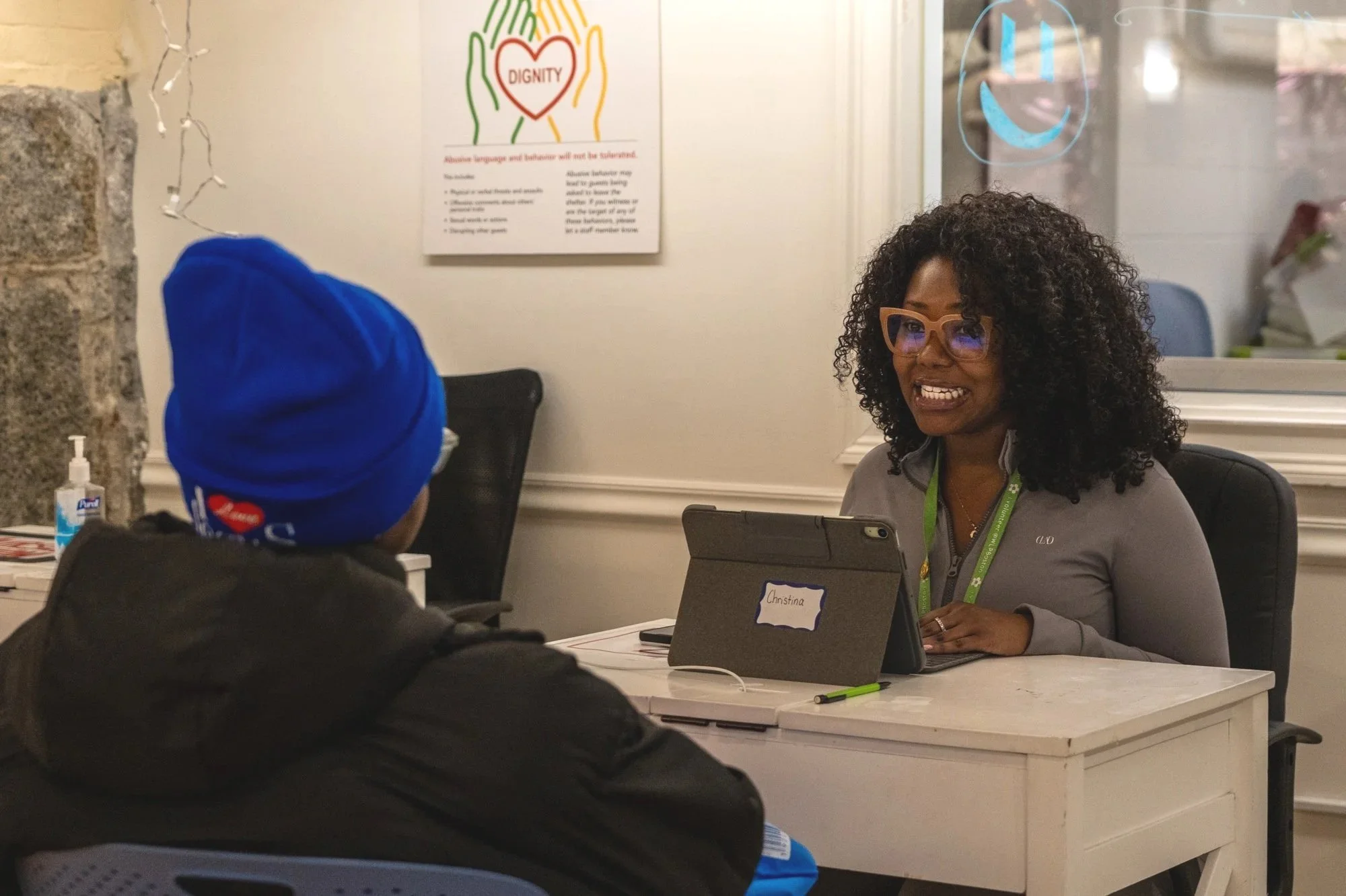 A case manager thoughtfully engages with a guest wearing winter clothing.