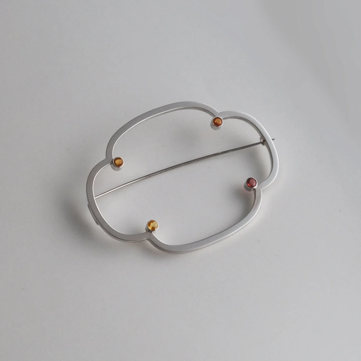 Bespoke silver brooch inspired by Japanese motifs with autumn-colored gemstones.