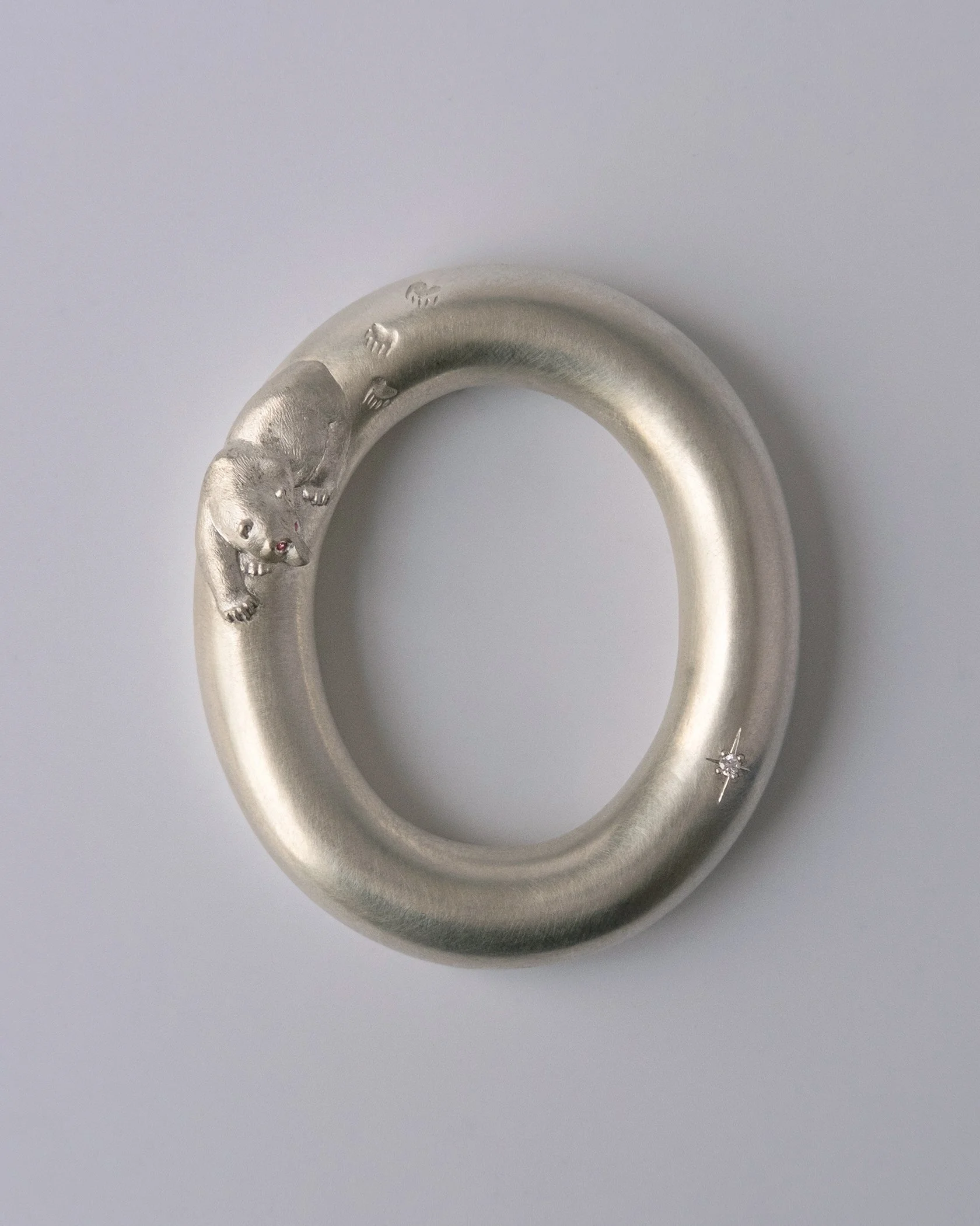 Silver baby rattle made by hand by goldsmith Julia Bocanet in Amsterdam, with a hand carved bear chasing a diamond star