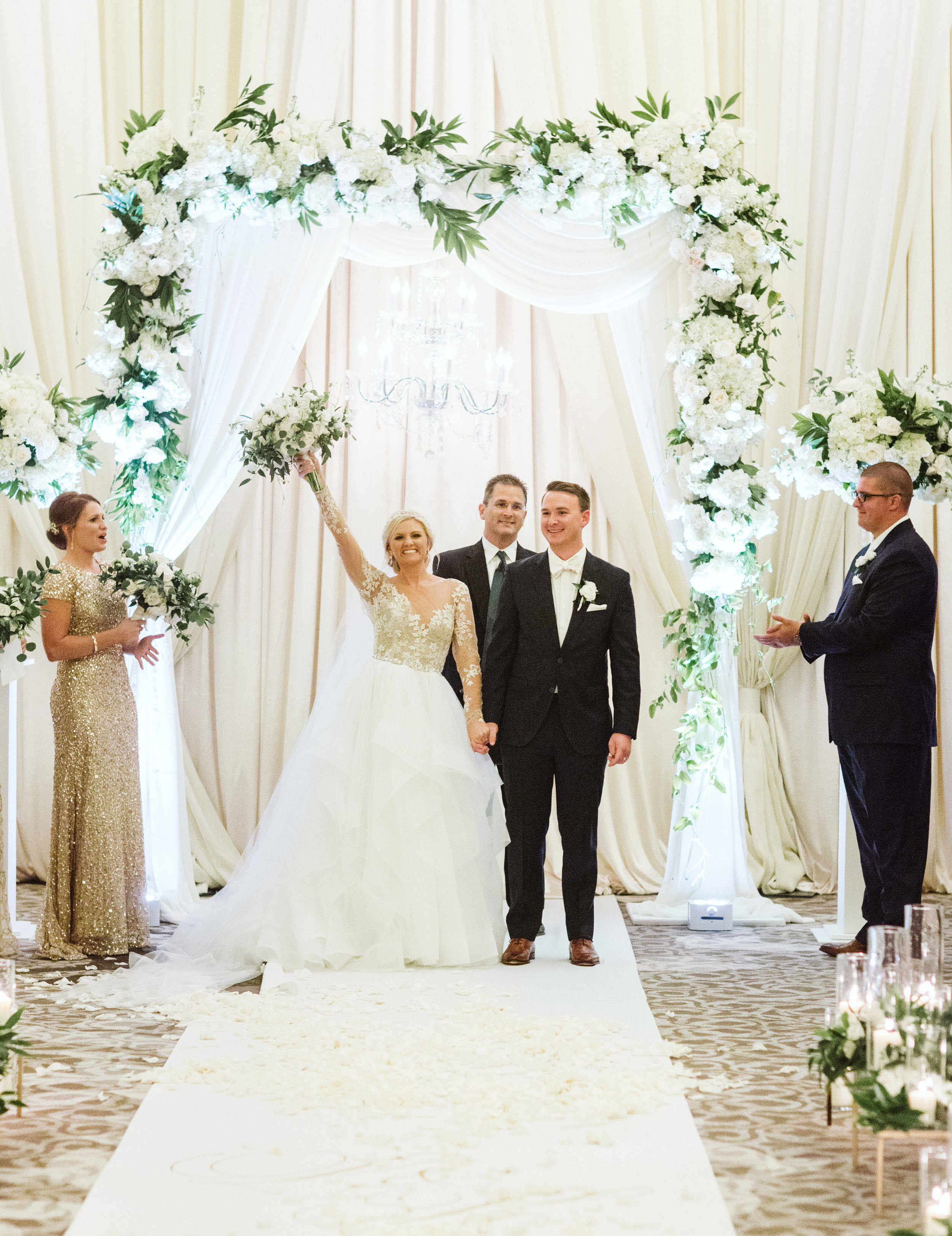 White and greenery ceremony structure with chandelier and hayley paige gown