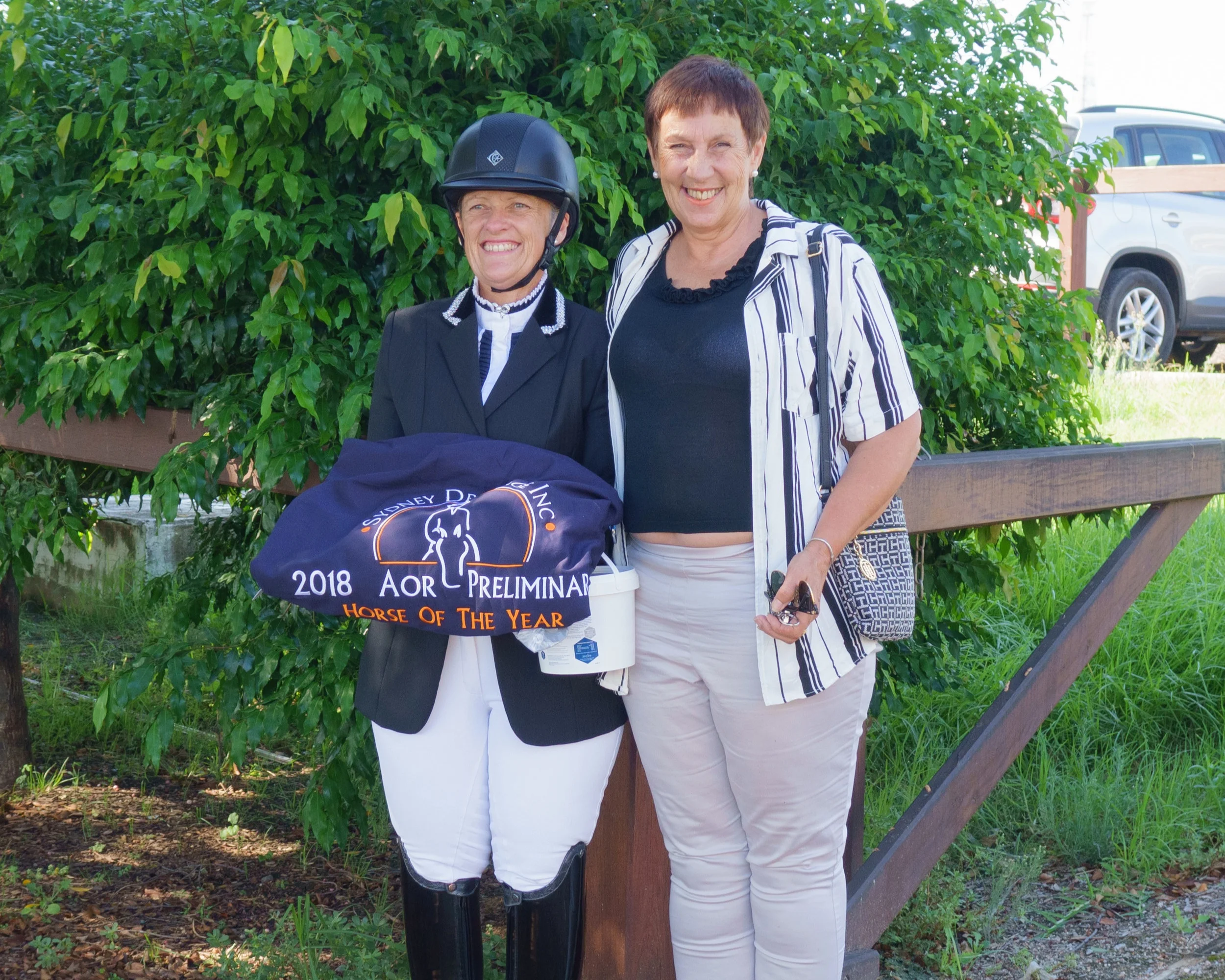 Jennifer wales holding the zilco trophy rug and equestrian news aor prize, photographed with zilco representative kelly king