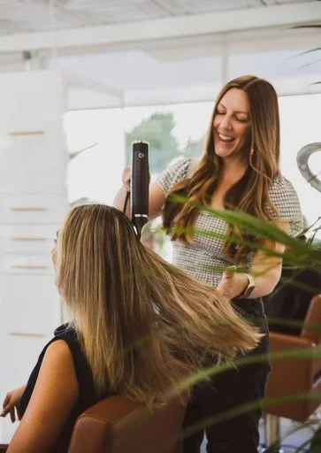 hairstylist blowdrying her client in a sunny san diego salon