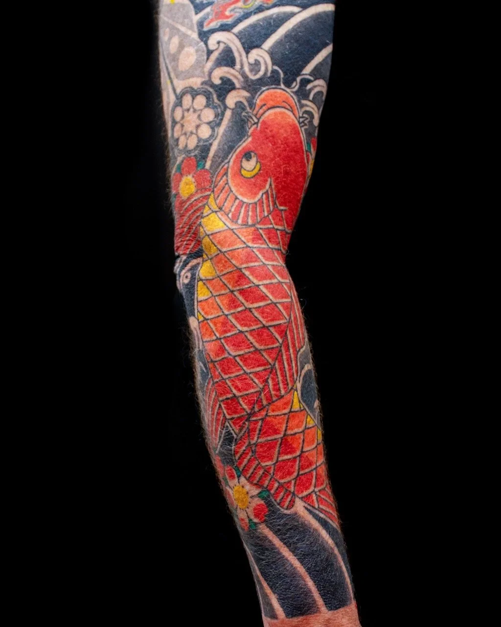 Traditional Japanese red koi sleeve tattoo with yellow details, sakura, waterfall and dark water-bar background by Horiyama in Auckland, New Zealand.