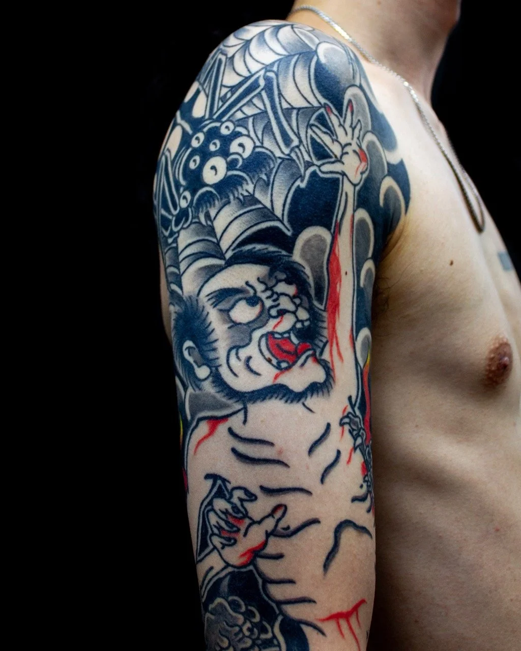 Close-up of a Japanese folklore tattoo sleeve by Horiyama, showing the central figure, spider thread and traditional Japanese tattoo shading.