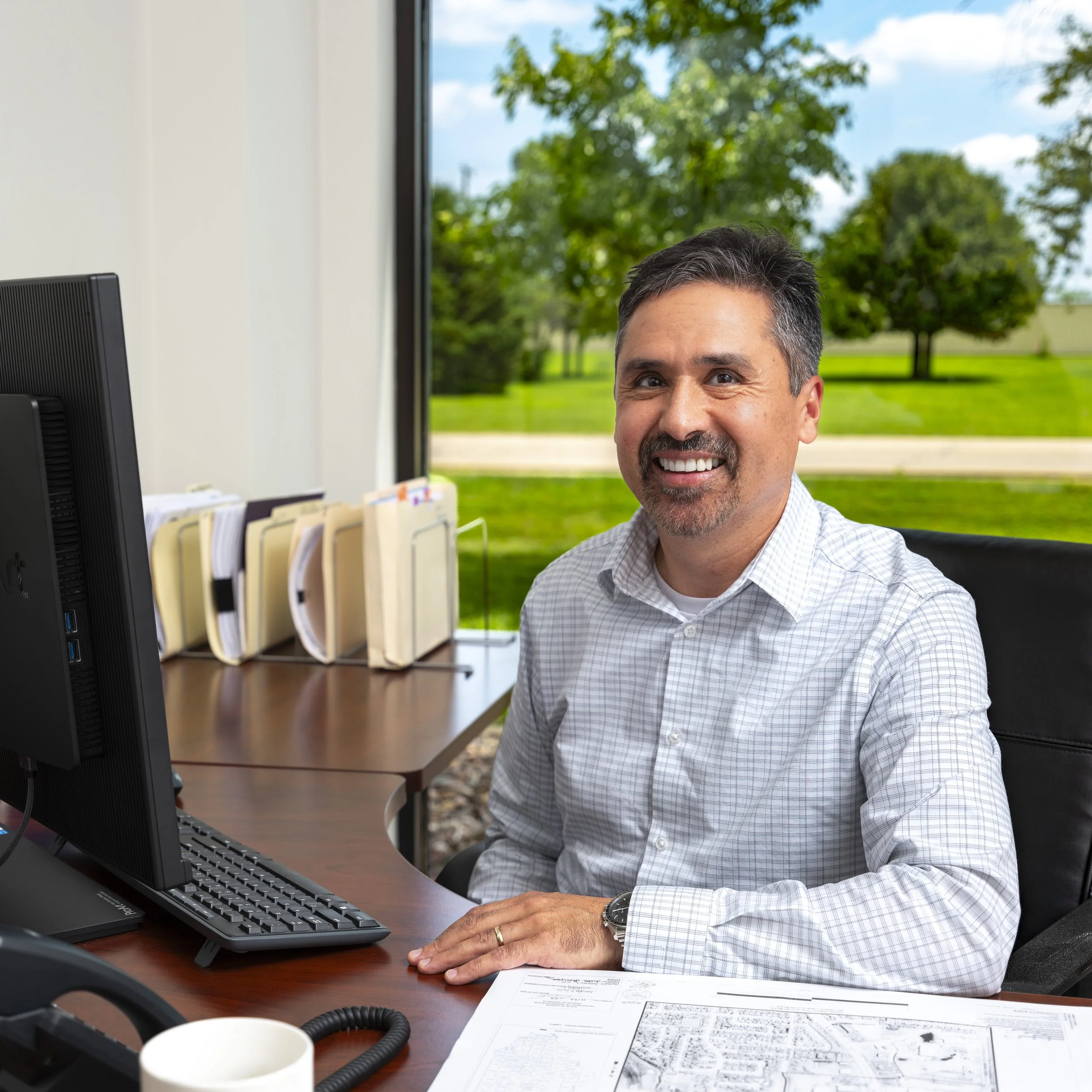 Environmental corporate portrait of a business executive seated at his desk in a modern office.