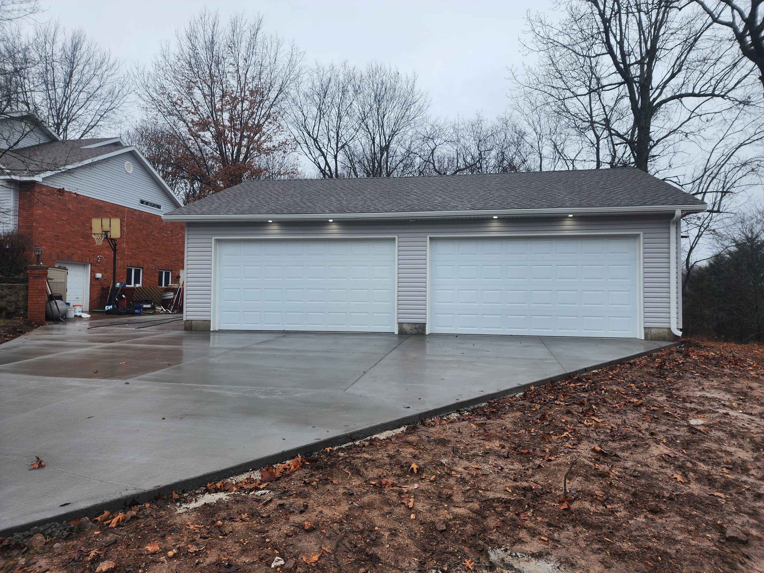  brand new double garage with white doors and gray siding 