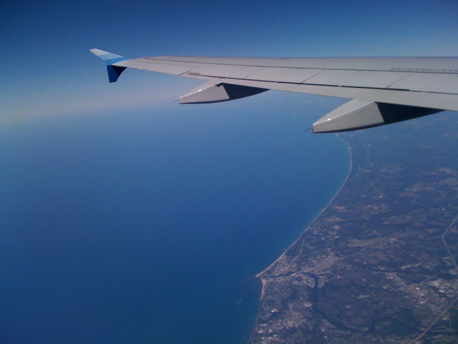airplane wing over land and water far below