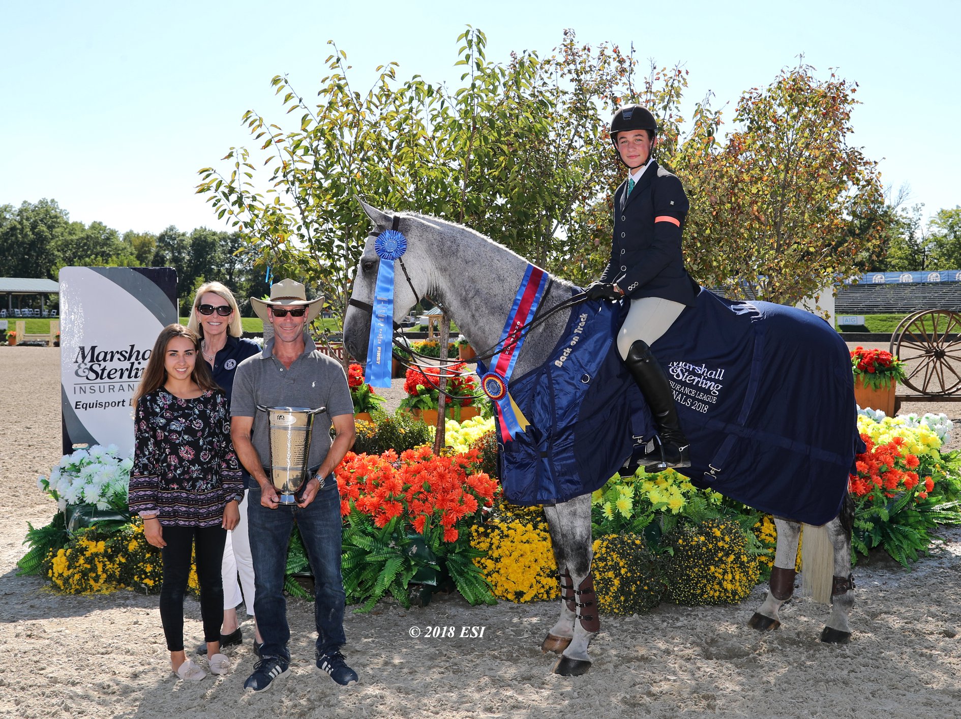 Gray horse and rider receiving championship awards from three presenters