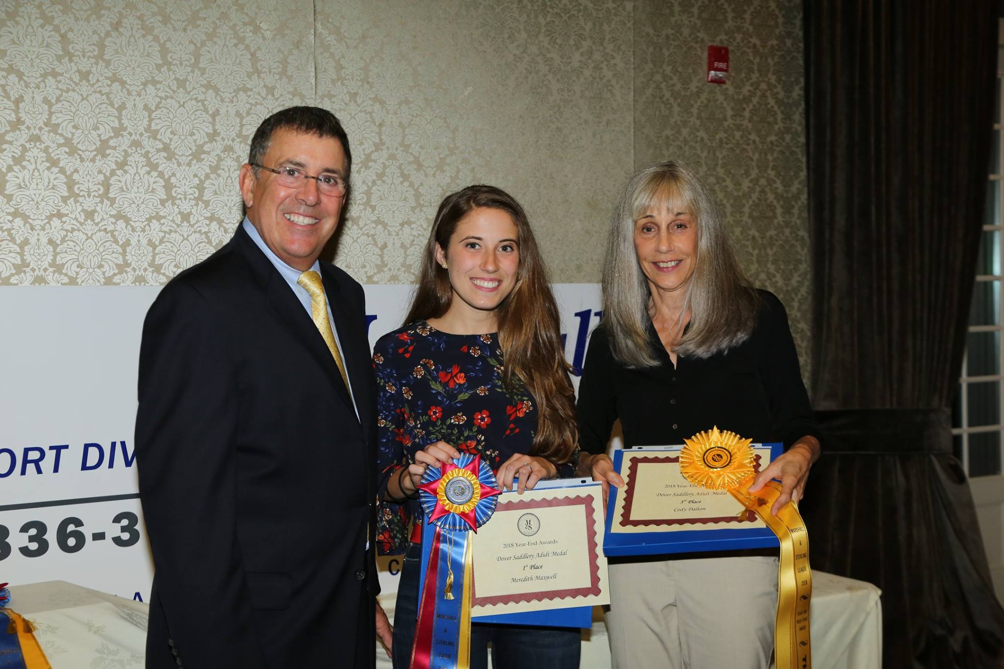 Don Graves presenting awards and ribbons to two women at a banquet