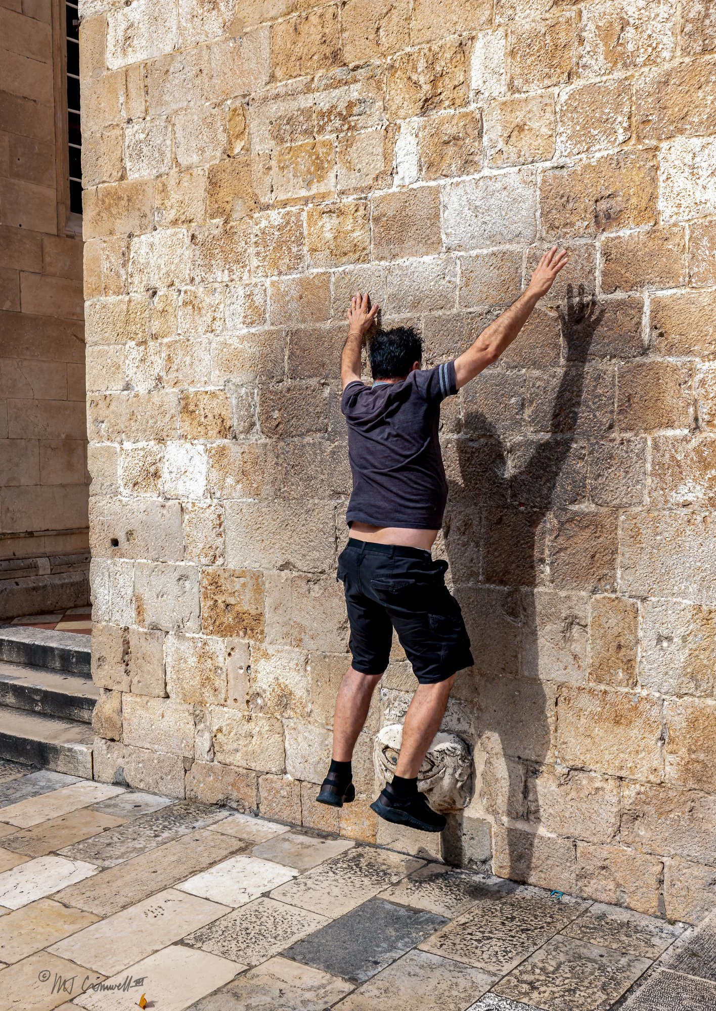 Dubrovnik visitor fails to stay up on balancing stone (known as the Dubrovnik Maskeron)