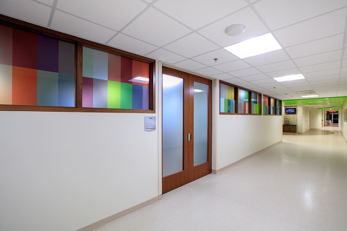 Colorful window film with a custom pattern provides privacy to a smaller, separate dining facility in the entrance corridor.