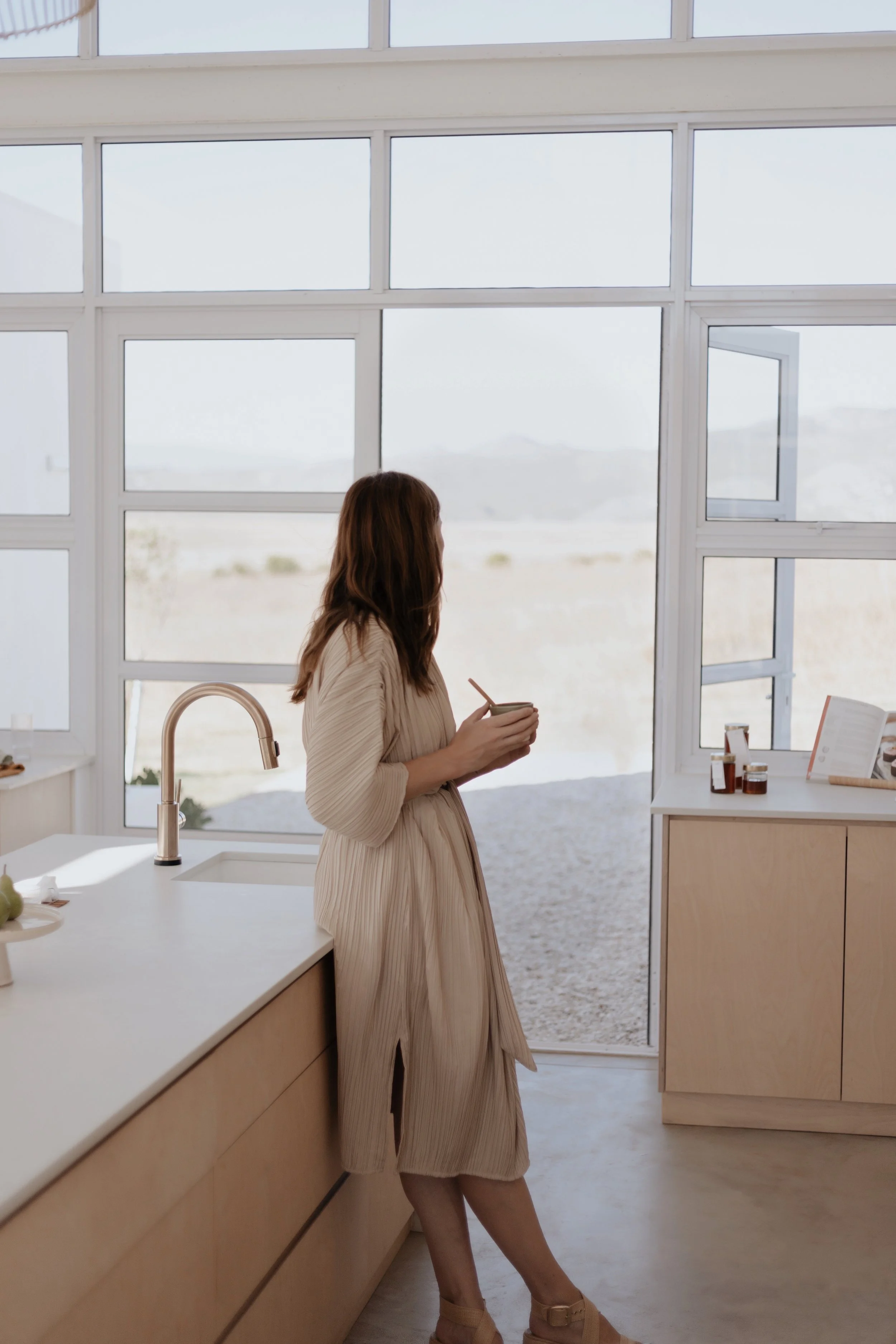 a woman with a morning coffee light filtering through the kitchen window.