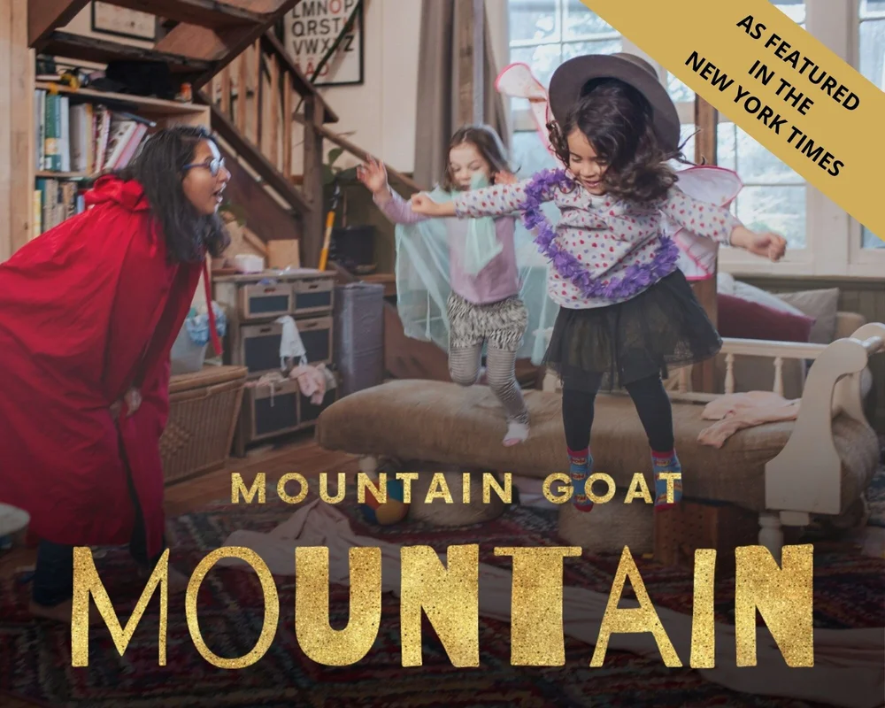 A young girl jumps of couch, her hat flies in the air. Her excited mother watches on in a red cape, as they enjoy Mountain Goat Mountain together.