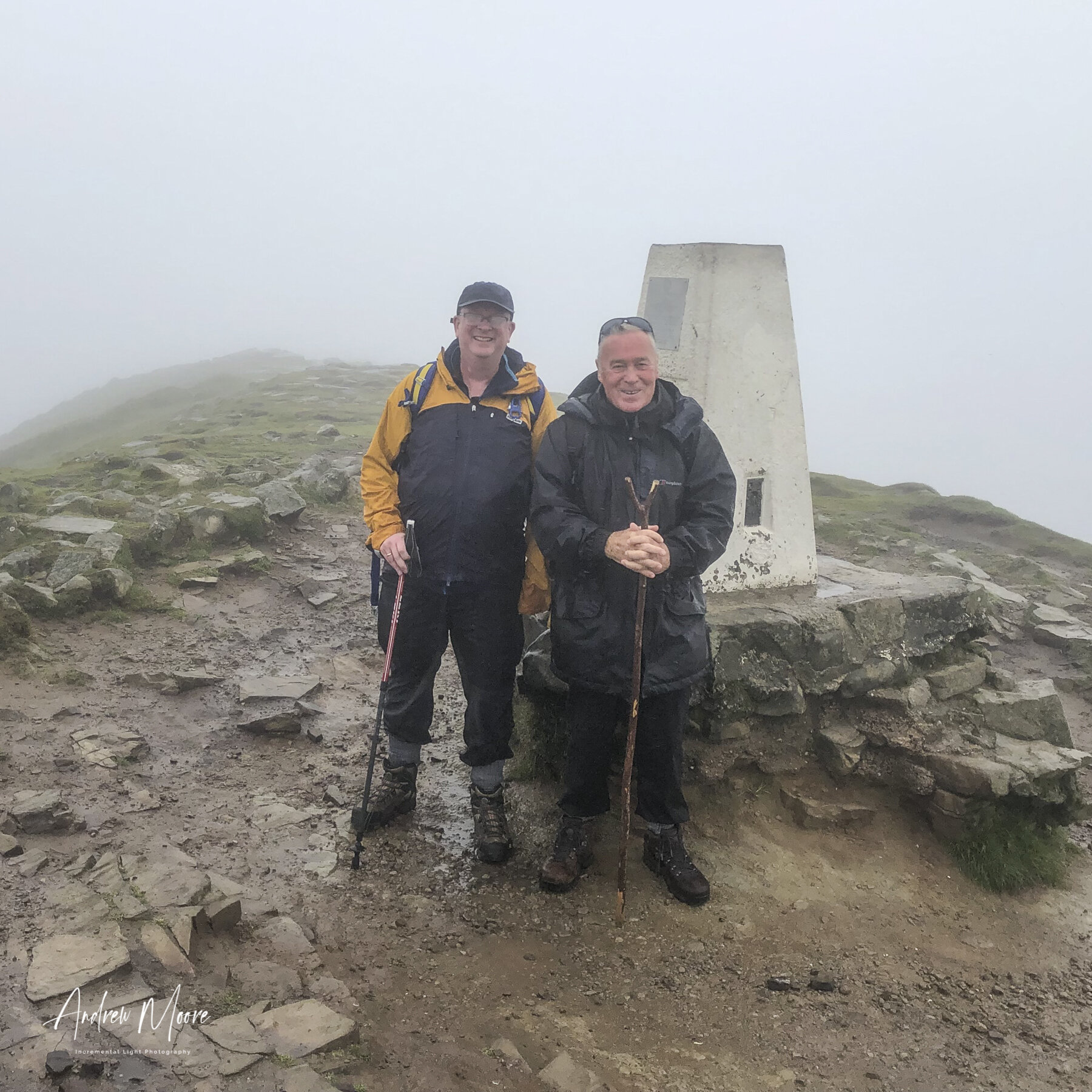 Fine Views From Here?Unfortunately as we reached the summit the clouds descended and the views were restricted to the hardy walkers and trig point.  Thank you to the chap that took this picture of us on my phone and didn’t run away with it.  By that point I was not in a position to give chase!