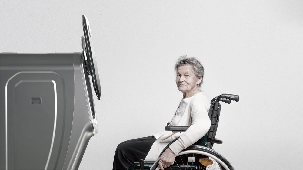  An open silver washing machine and a woman in a wheelchair facing it 