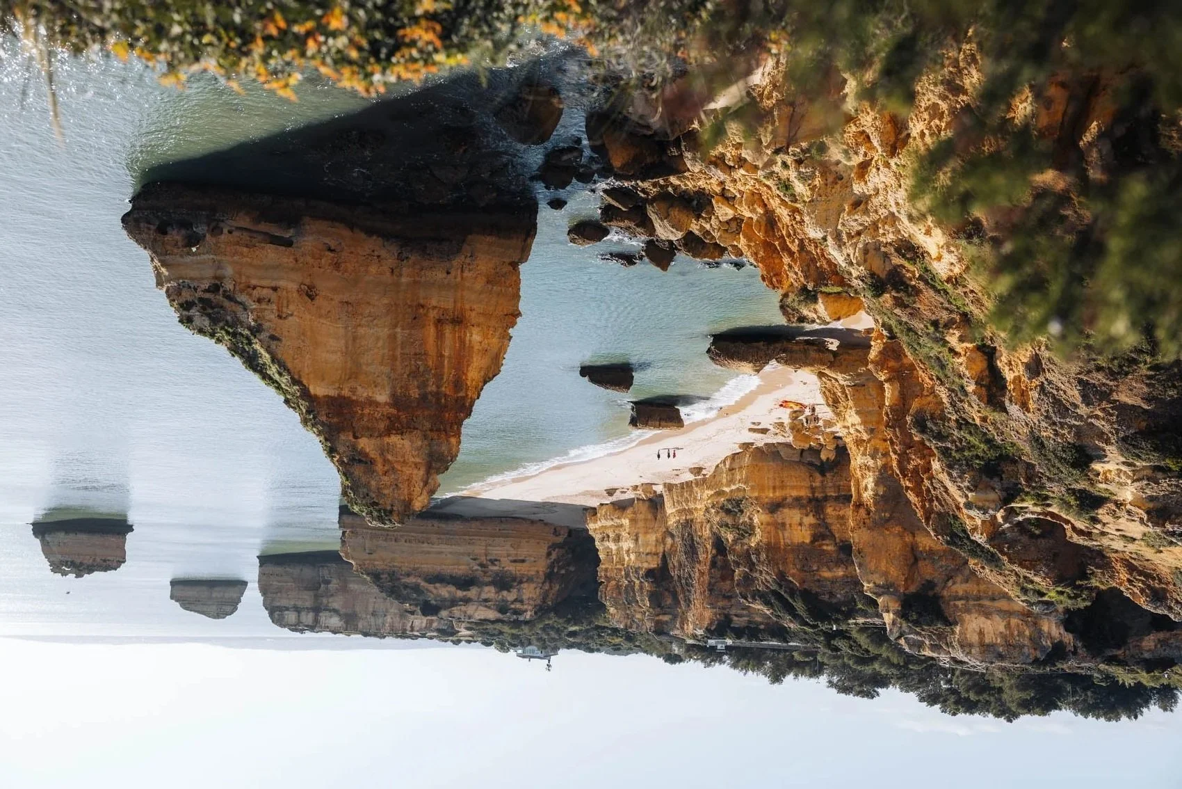 Une plage avec des formations rocheuses imposantes et des falaises rocheuses côtières avec de la végétation, vue depuis la mer