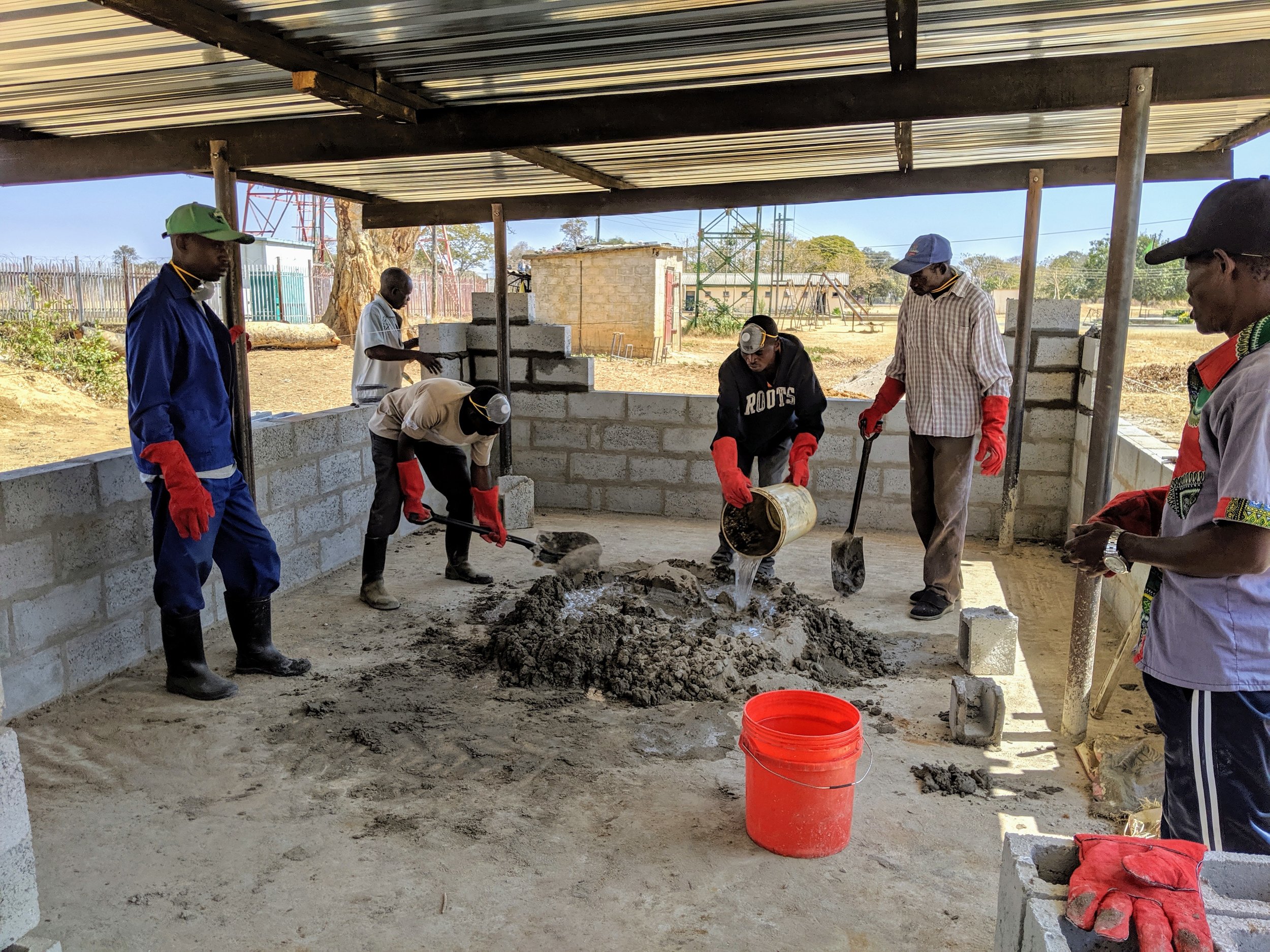 Mixing concrete to finish the wall in the background